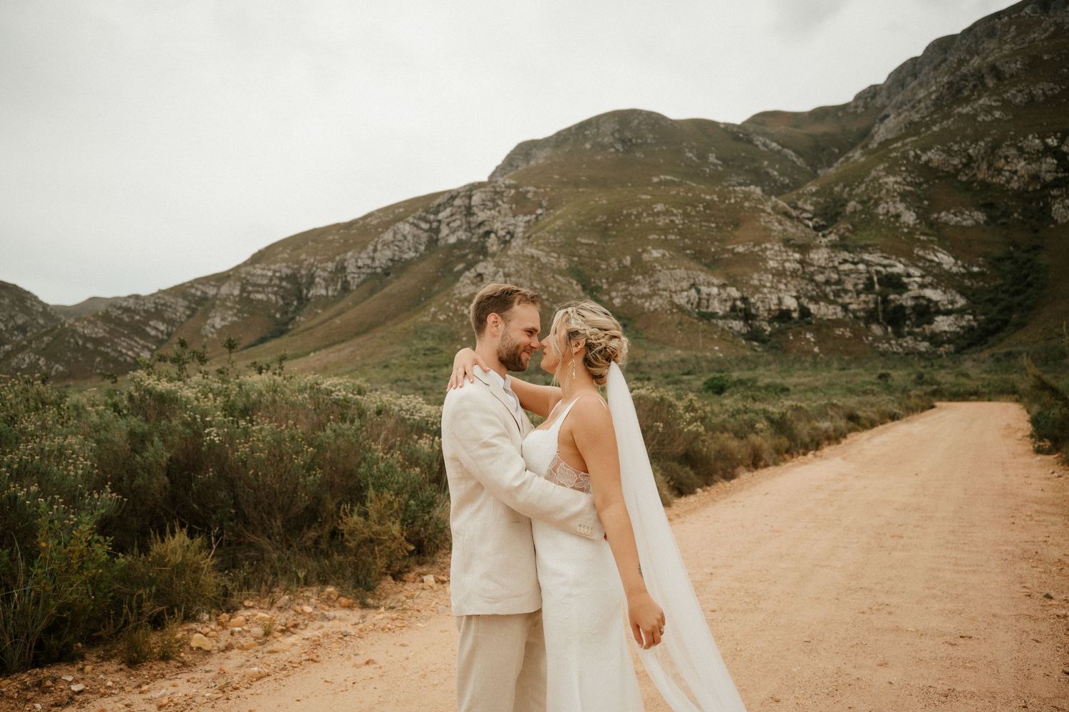 A wedding moment captured on a mountain path with dramatic rocky cliffs and natural scenery.