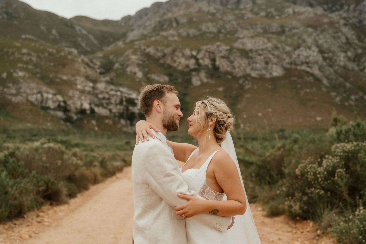 A romantic wedding portrait on a mountain trail during golden hour.