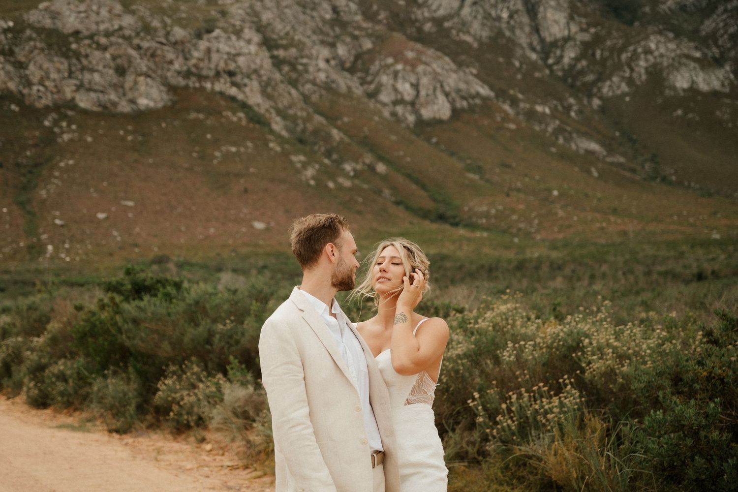 A joyful wedding moment captured on a mountain path during sunset.