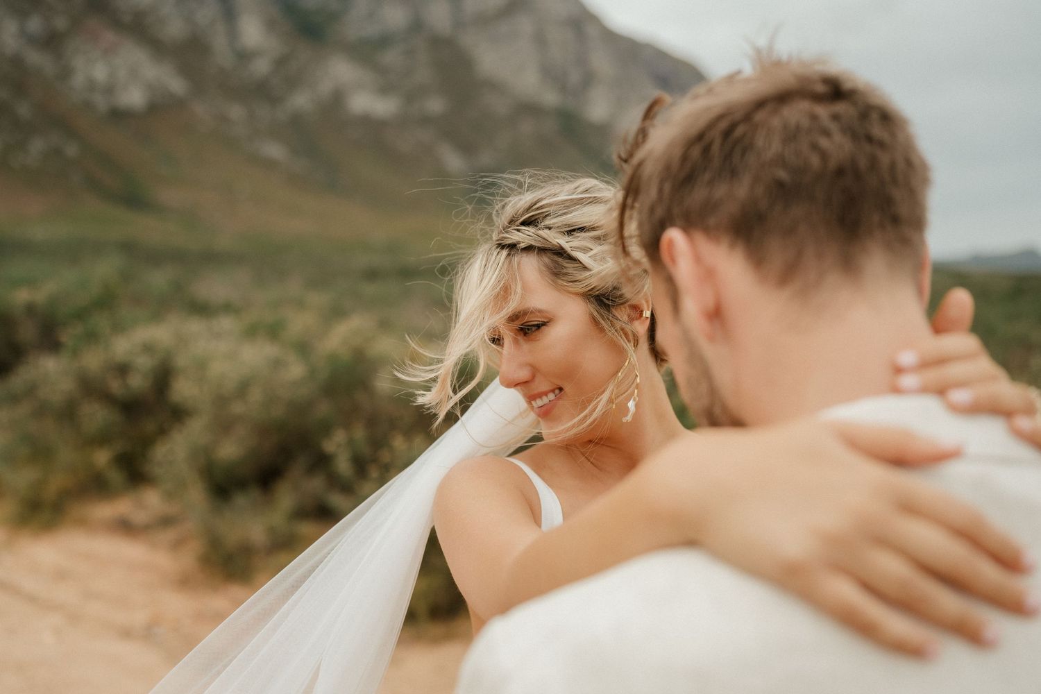Close-up moment of a tender embrace captured against mountain scenery.