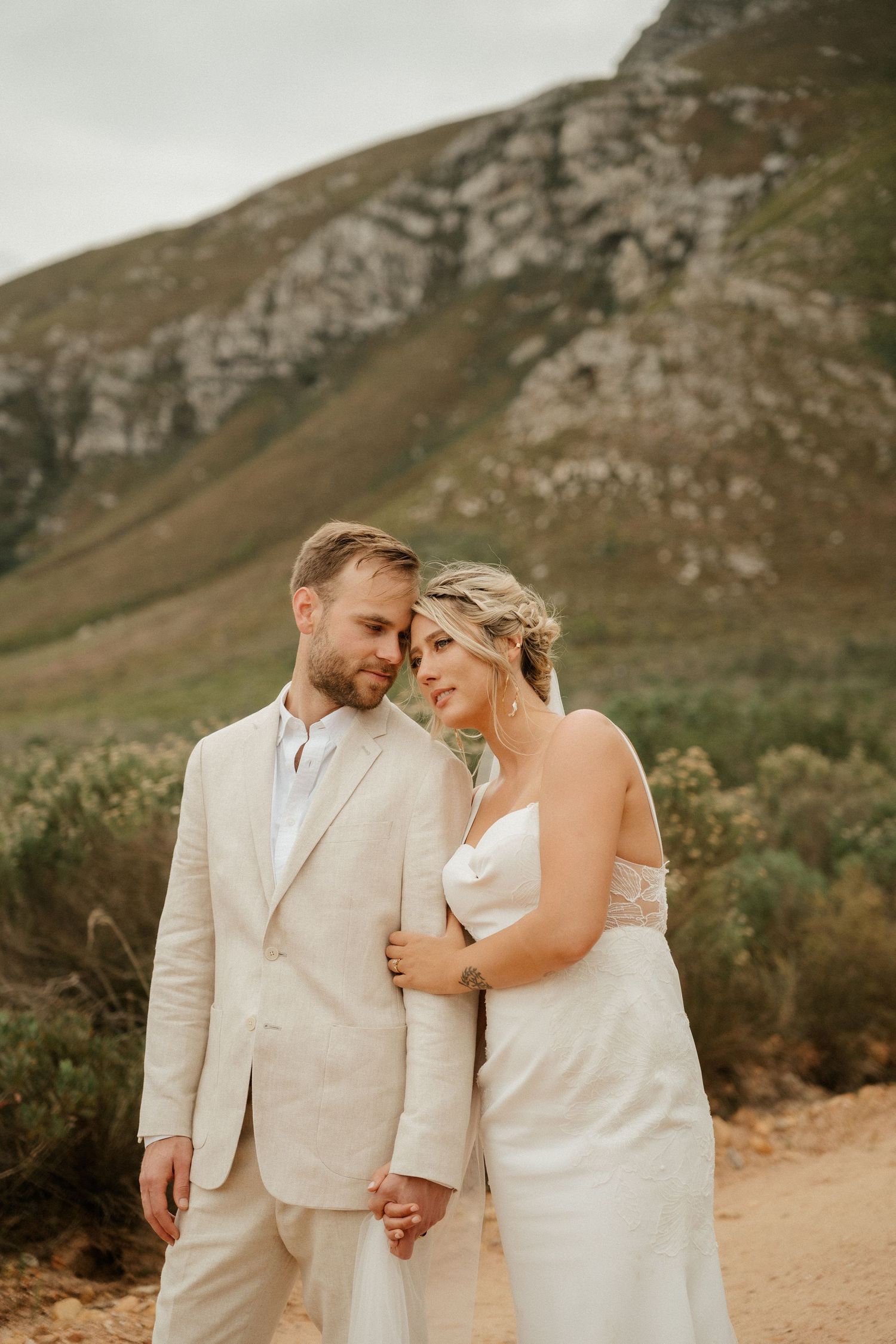 A tender wedding moment captured against rugged mountain backdrop at golden hour.