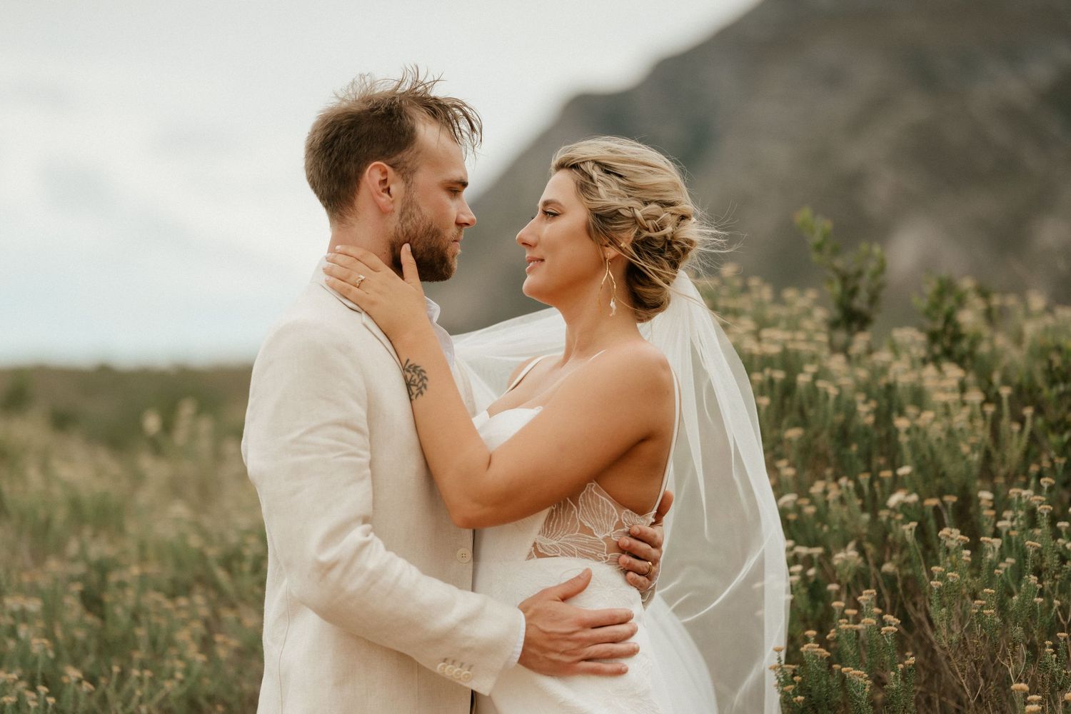 Intimate wedding portrait with couple embracing against mountain landscape.