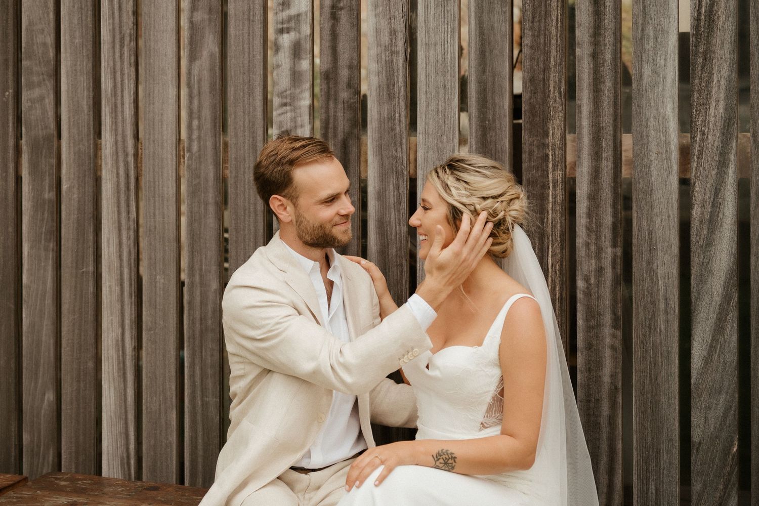 Intimate wedding moment captured against rustic wooden wall backdrop.