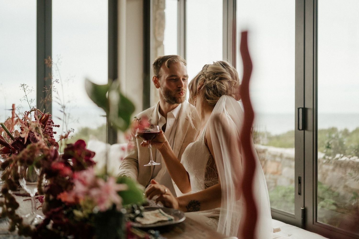 A joyful wedding celebration captured through window reflections with pink floral arrangements.