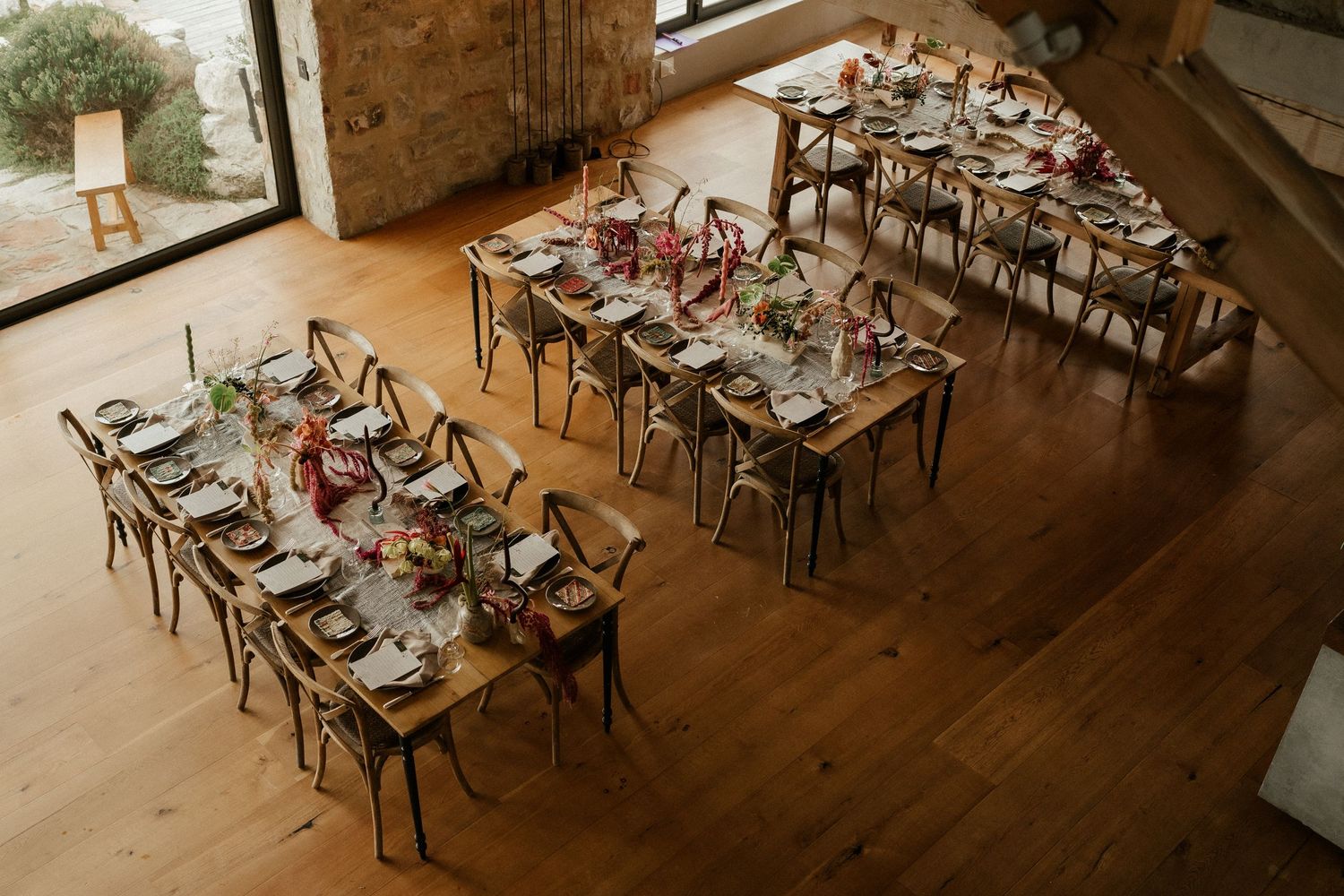 Elegant rustic wedding reception tables set with floral centerpieces in a wooden barn venue.