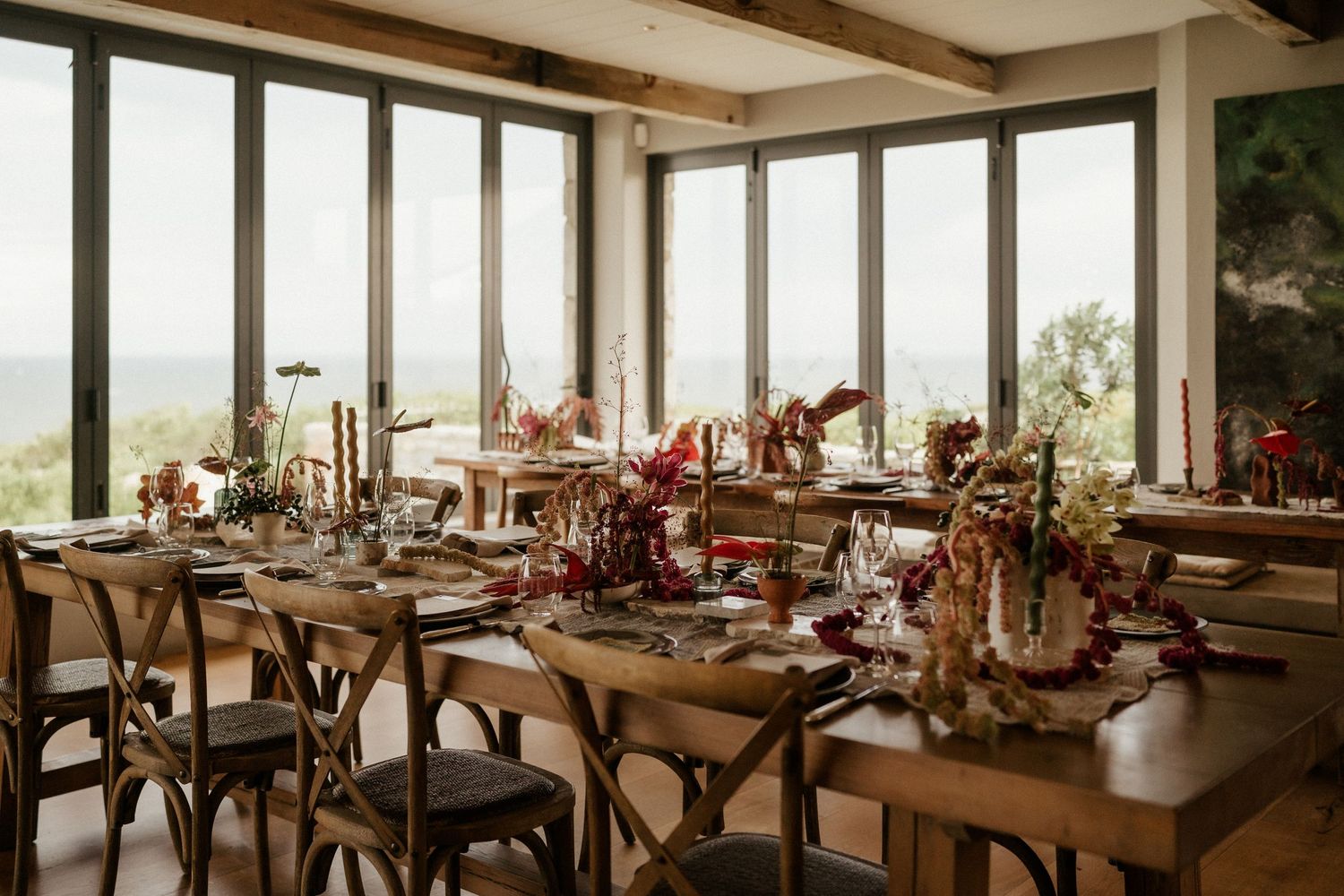 Elegant wedding reception table setting with floral centerpieces and natural light streaming through windows.