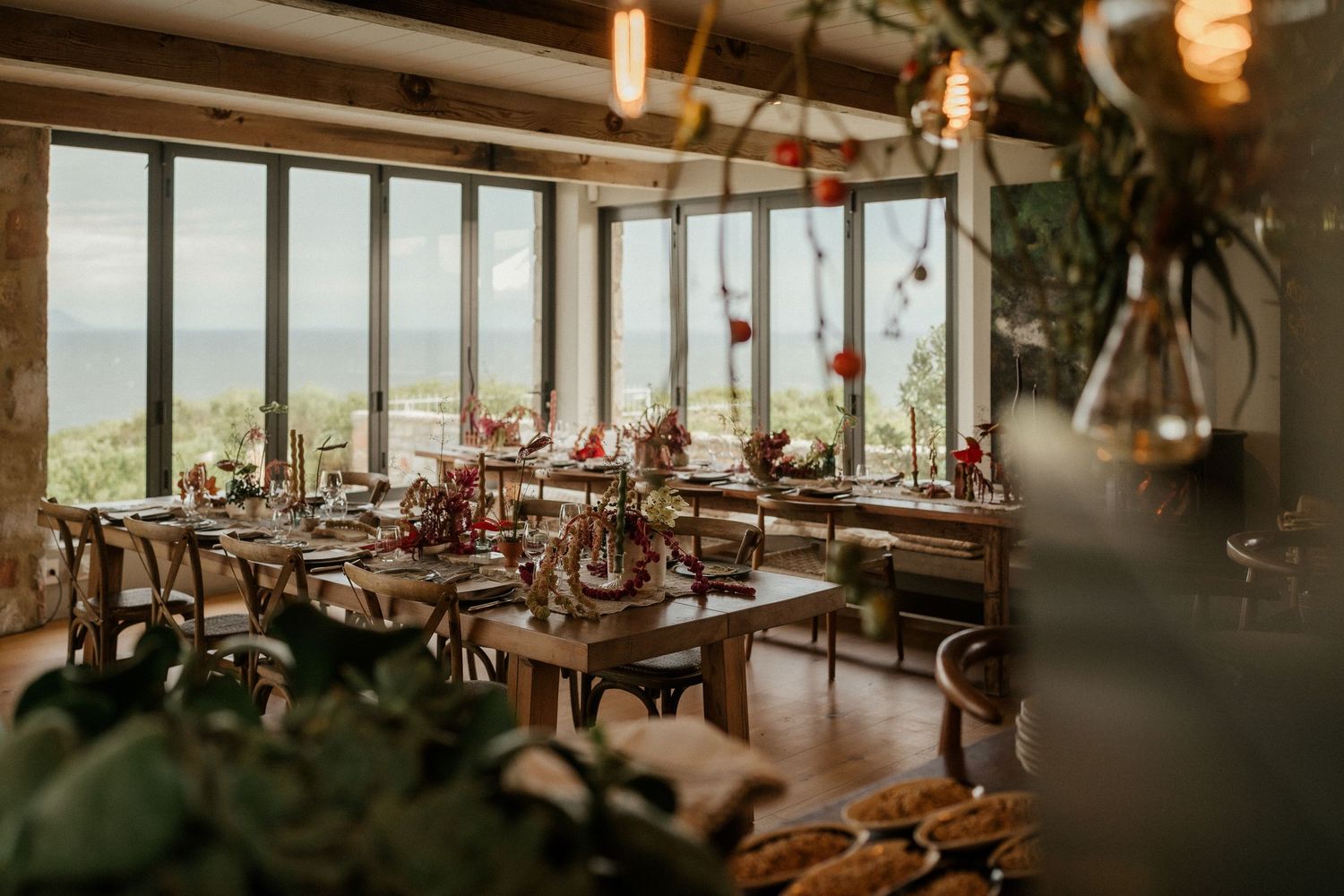 An elegantly decorated wedding reception venue with panoramic windows overlooking a scenic landscape.