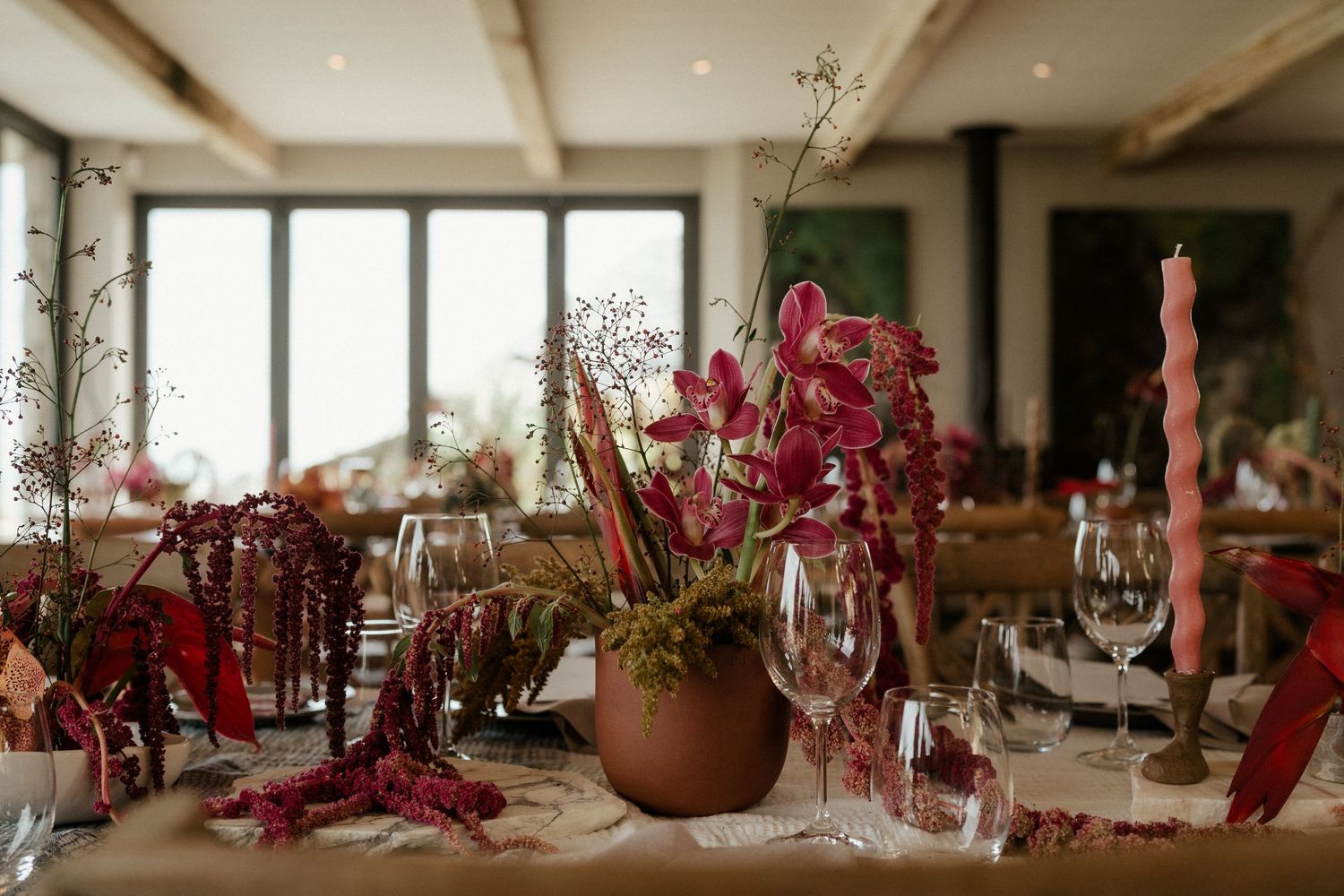 Elegant wedding table setting with red floral centerpieces and crystal wine glasses.