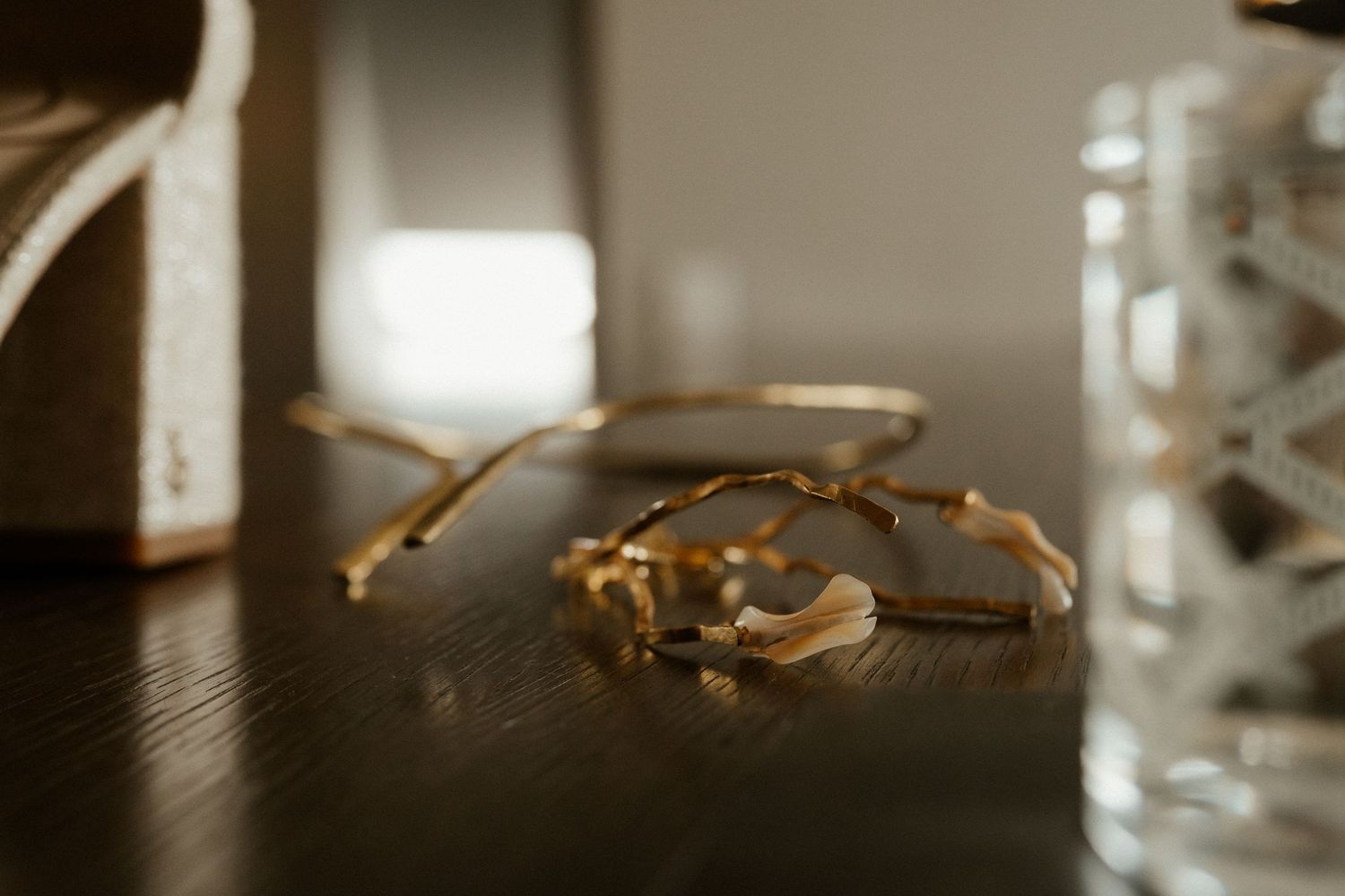 Vintage gold-rimmed eyeglasses lying on a dark wooden surface in soft focus.