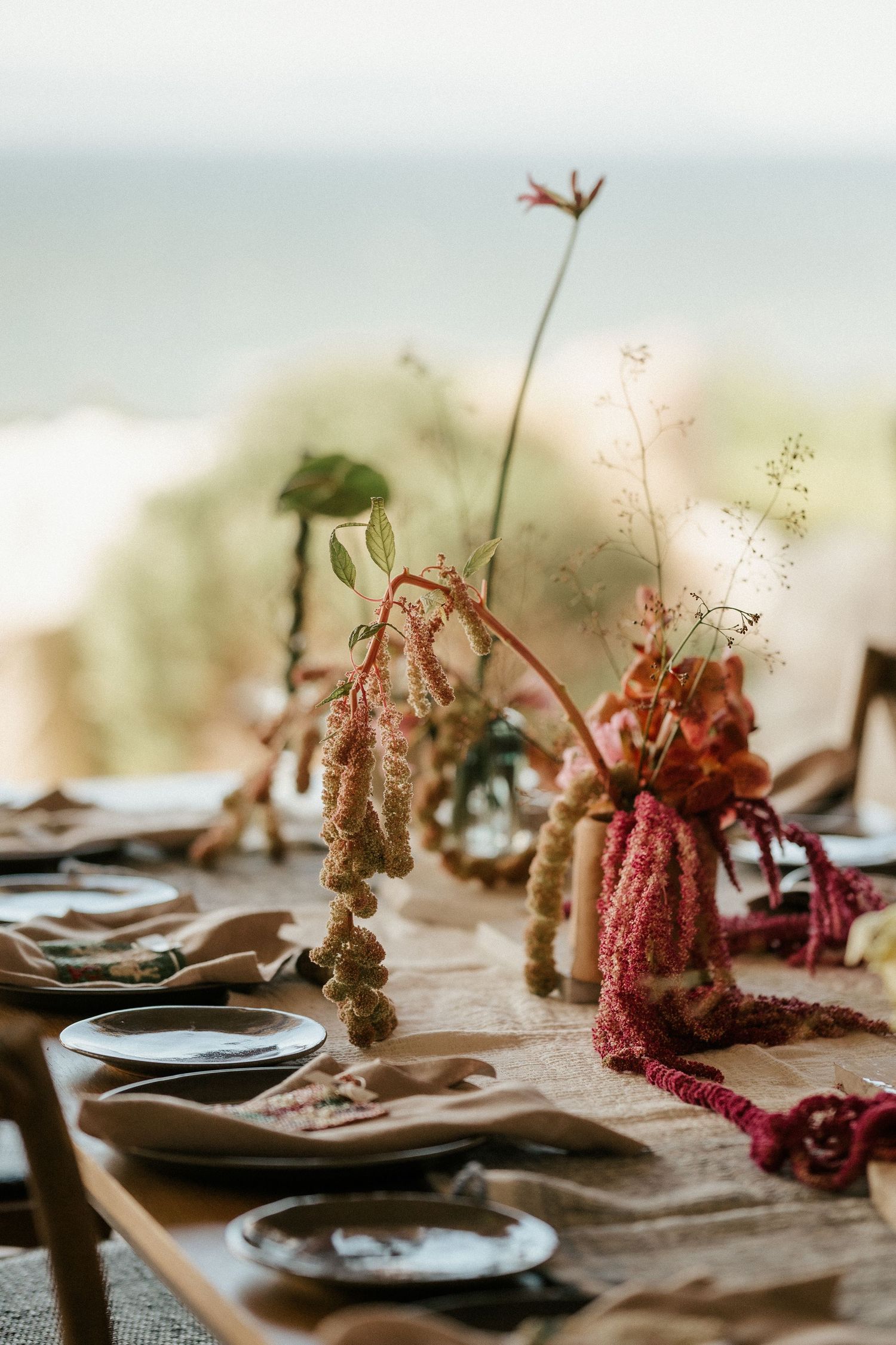 Close-up of dried floral arrangements and place settings on a rustic table.