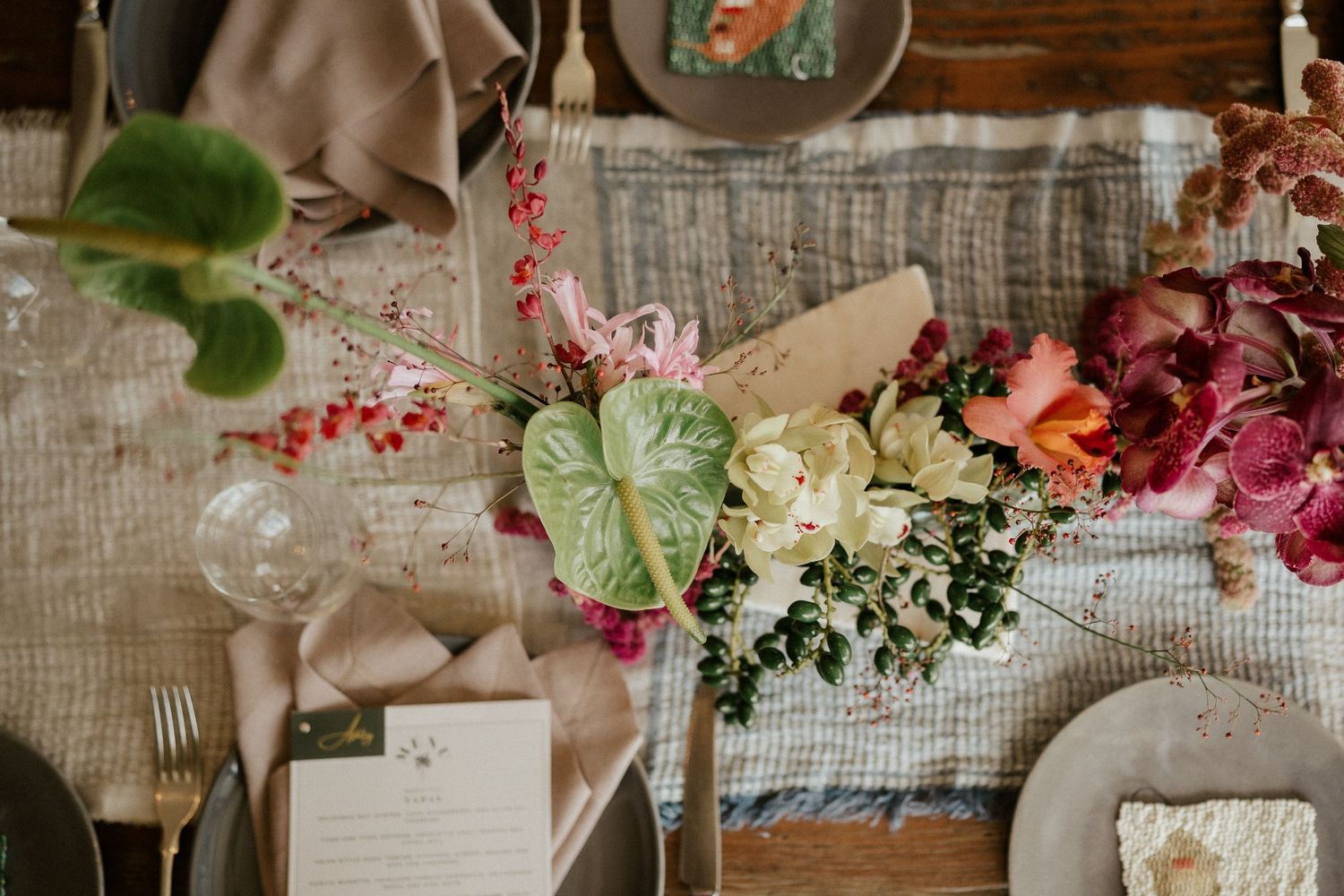 Wedding table decor featuring lush floral arrangements with greenery and berries on textured linens.