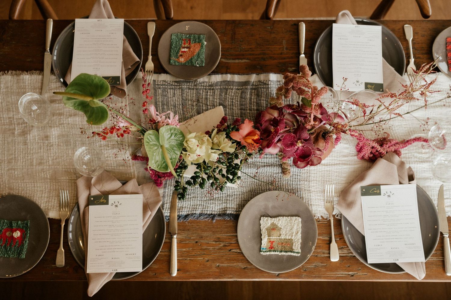 Elegant rustic wedding table setting with pink floral arrangements and place settings on wooden tables.