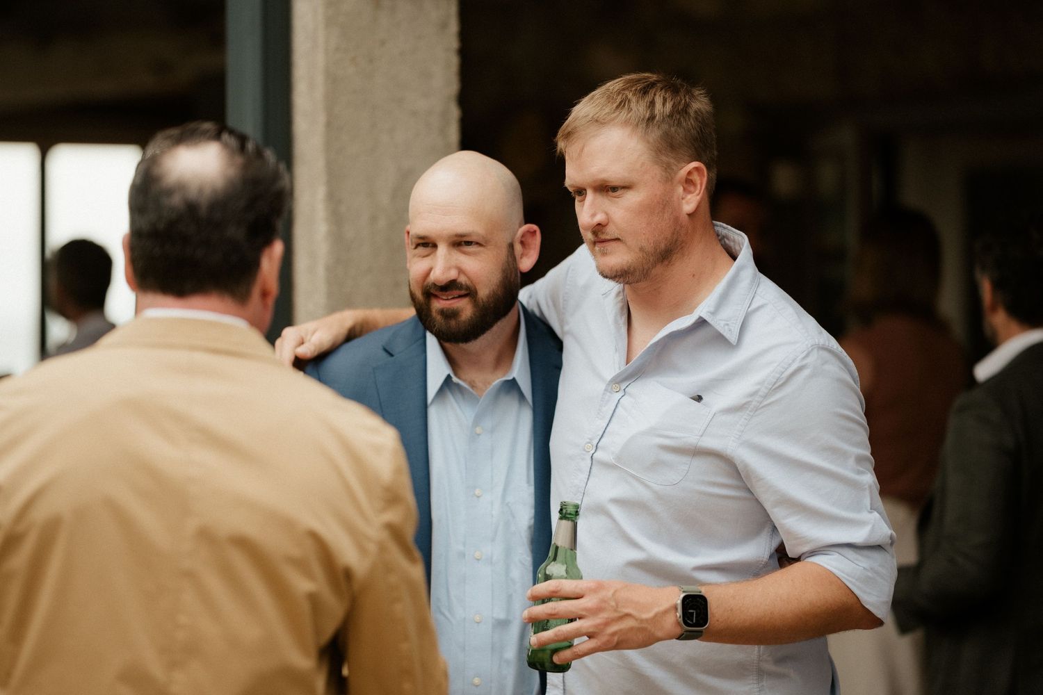 Three men engaged in casual conversation at what appears to be a wedding reception.