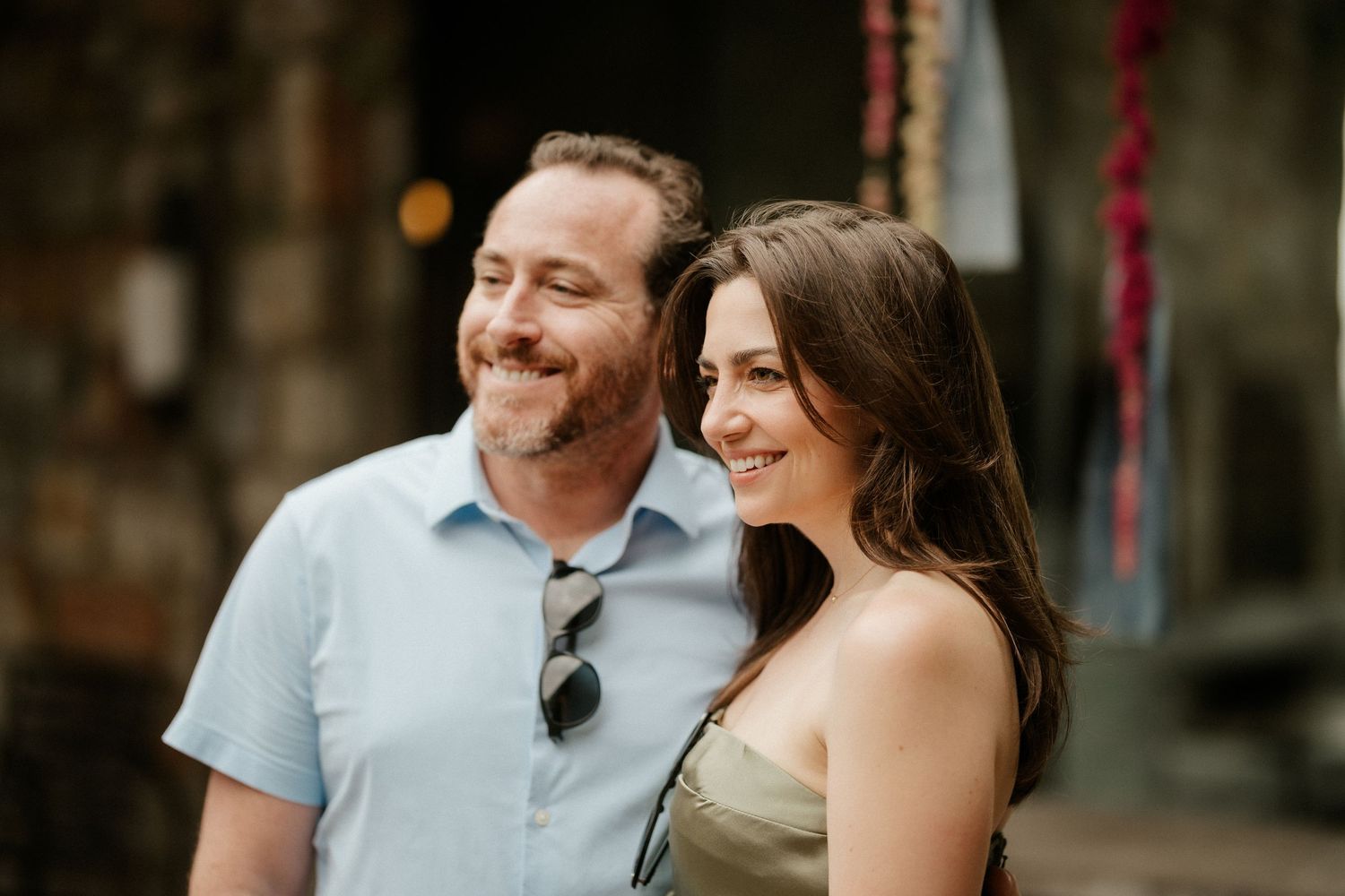 A couple shares a joyful moment outdoors with natural bokeh lighting in the background.
