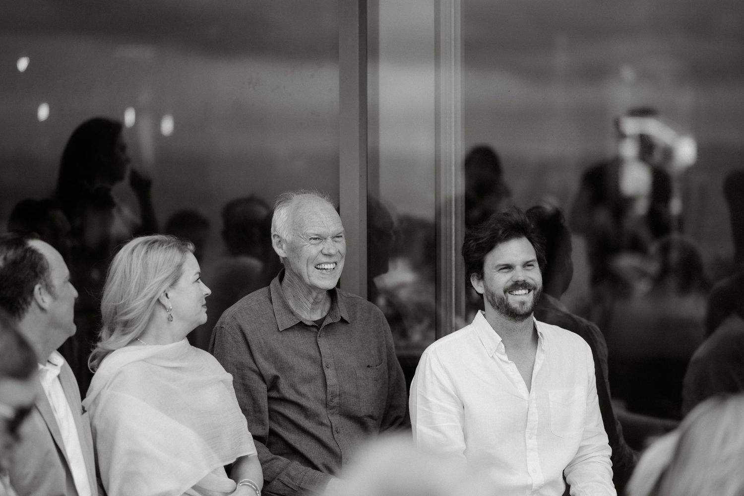 A candid black and white photo of guests laughing during a social gathering.