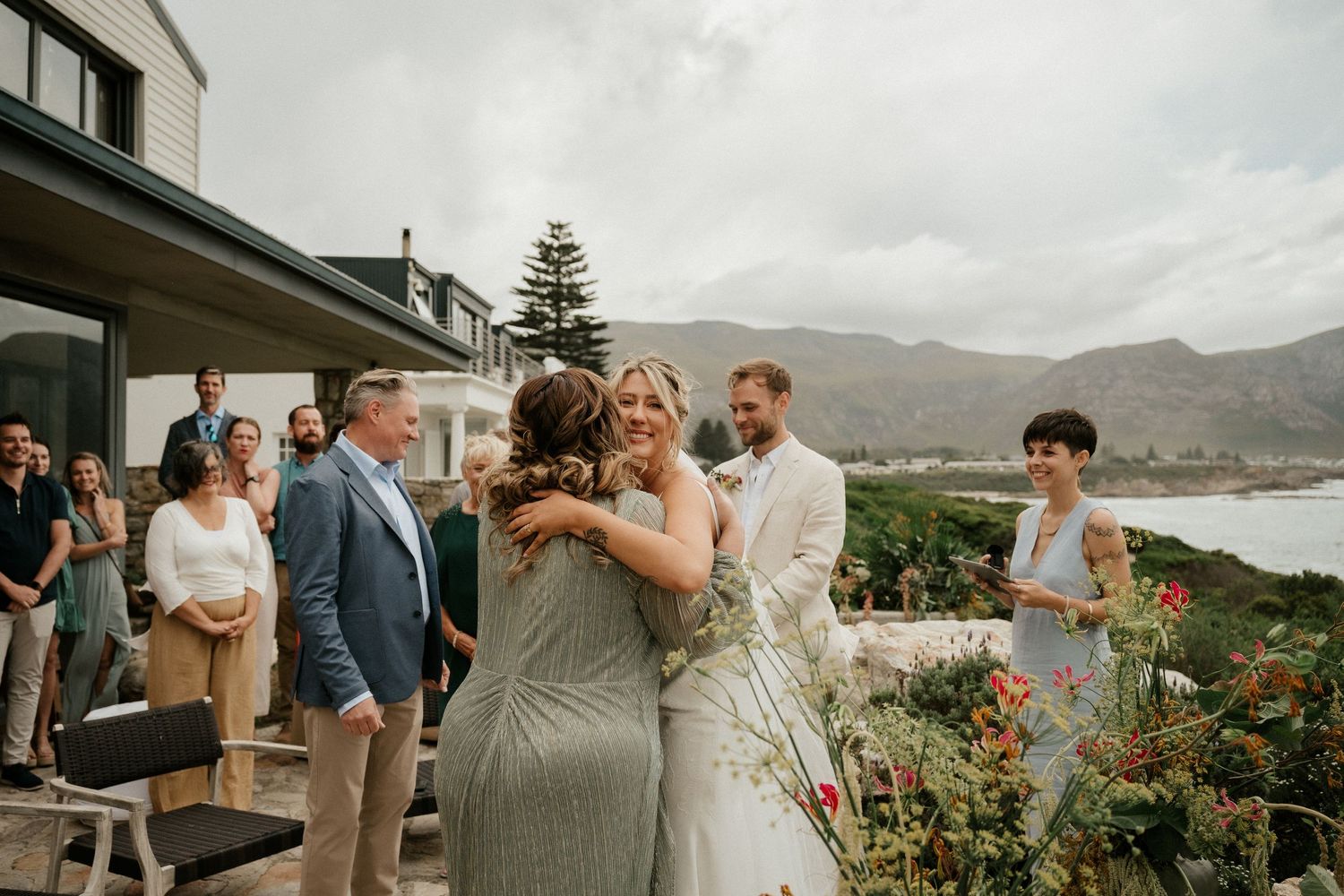 Celebratory moment at an outdoor wedding reception with mountains and lake creating a scenic backdrop.