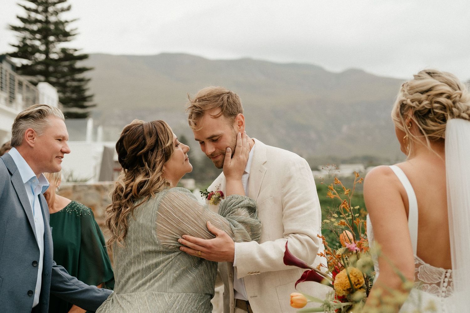 Emotional wedding celebration moment outdoors with mountain scenery.