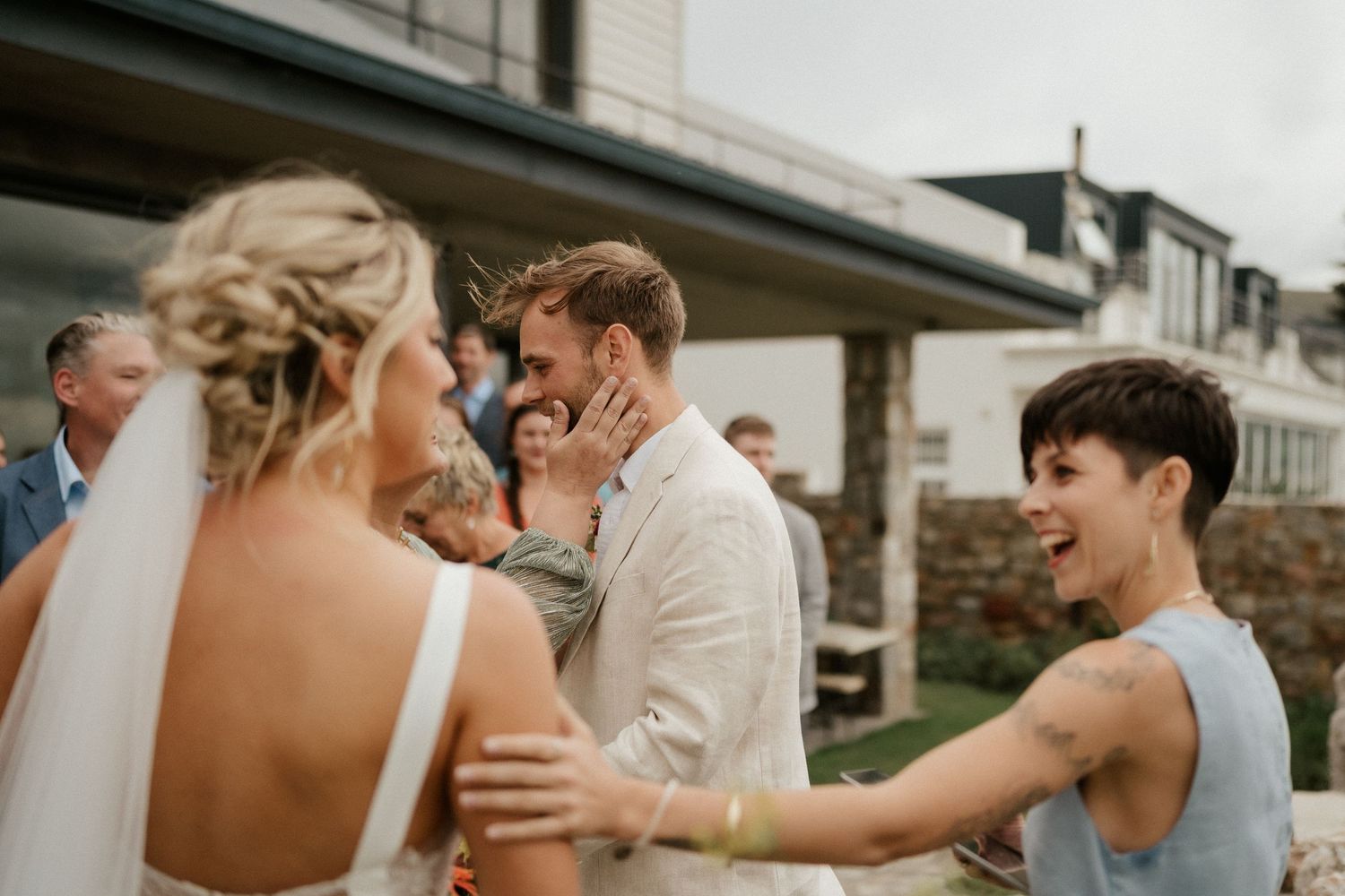 A celebratory moment at an outdoor wedding reception as guests share joyful laughter and warm embraces.