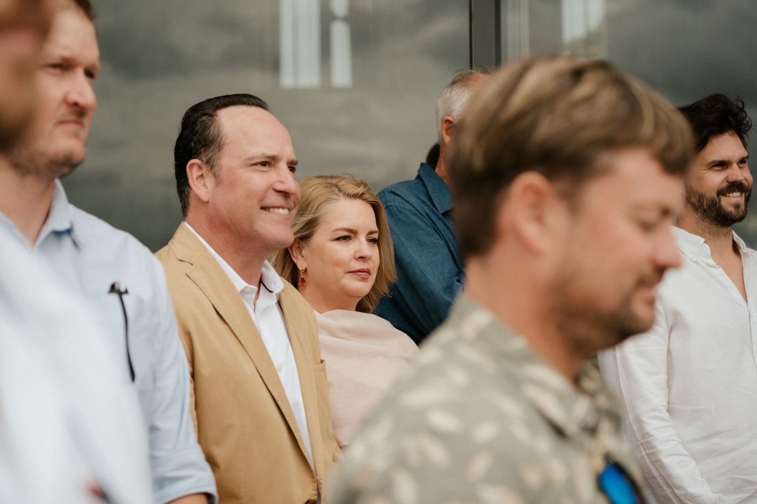 Wedding guests in casual attire stand together during an outdoor celebration.