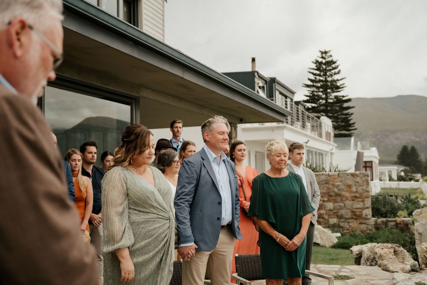 Casual outdoor gathering of wedding guests against a mountain backdrop.