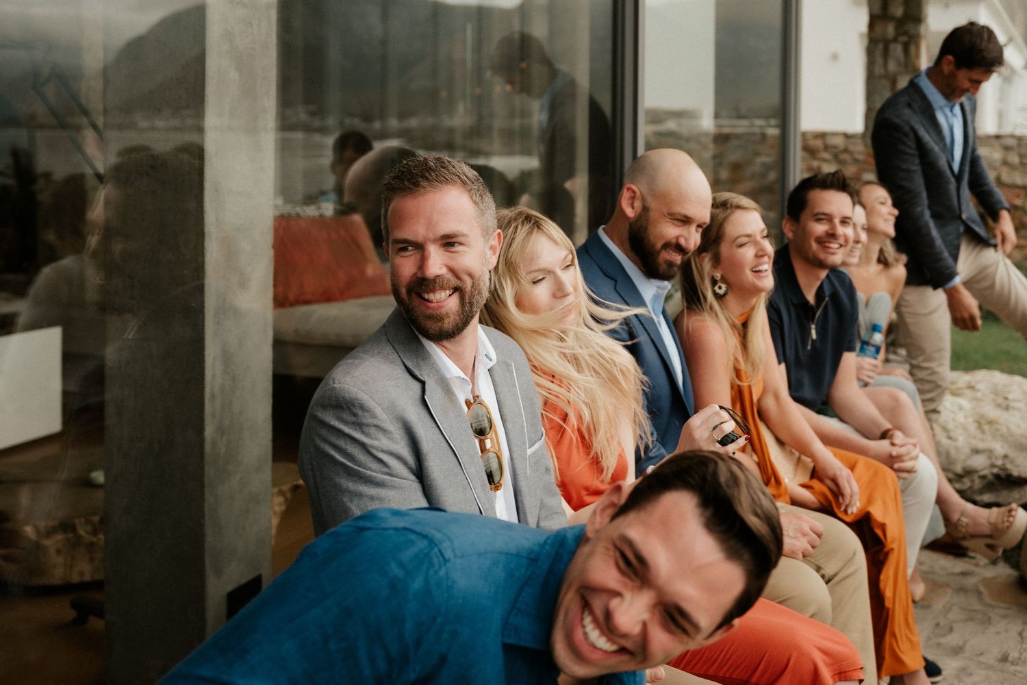 Wedding guests relaxing and smiling at an outdoor ceremony with modern architectural elements.