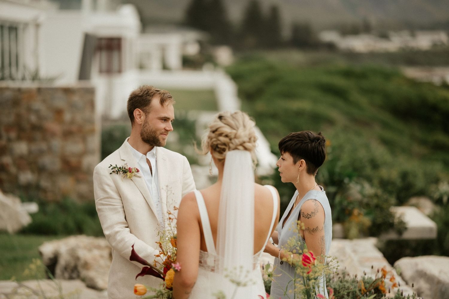 Intimate outdoor wedding ceremony moment on a hillside with mountains in background.