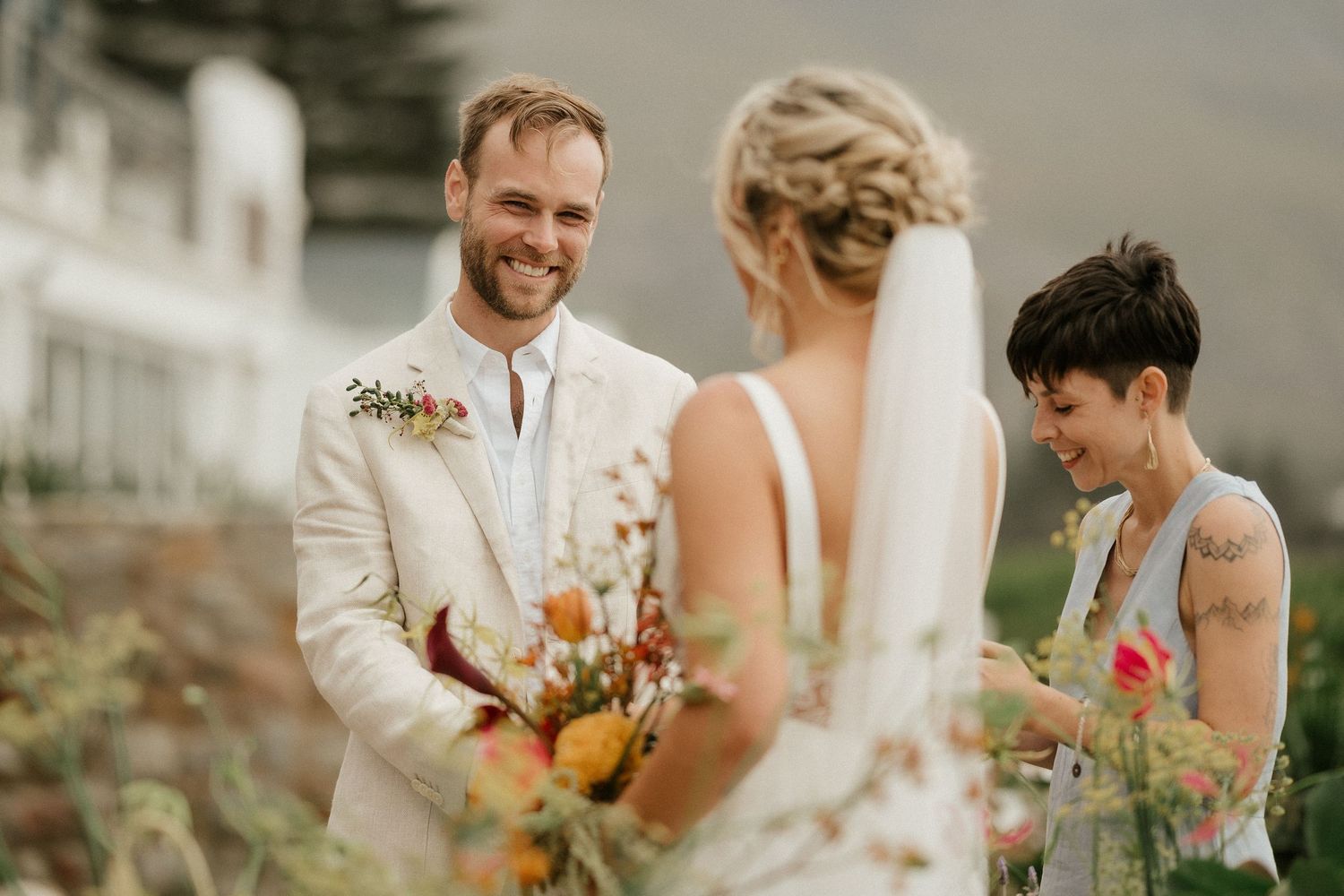 An intimate wedding ceremony moment surrounded by coastal flowers and greenery.