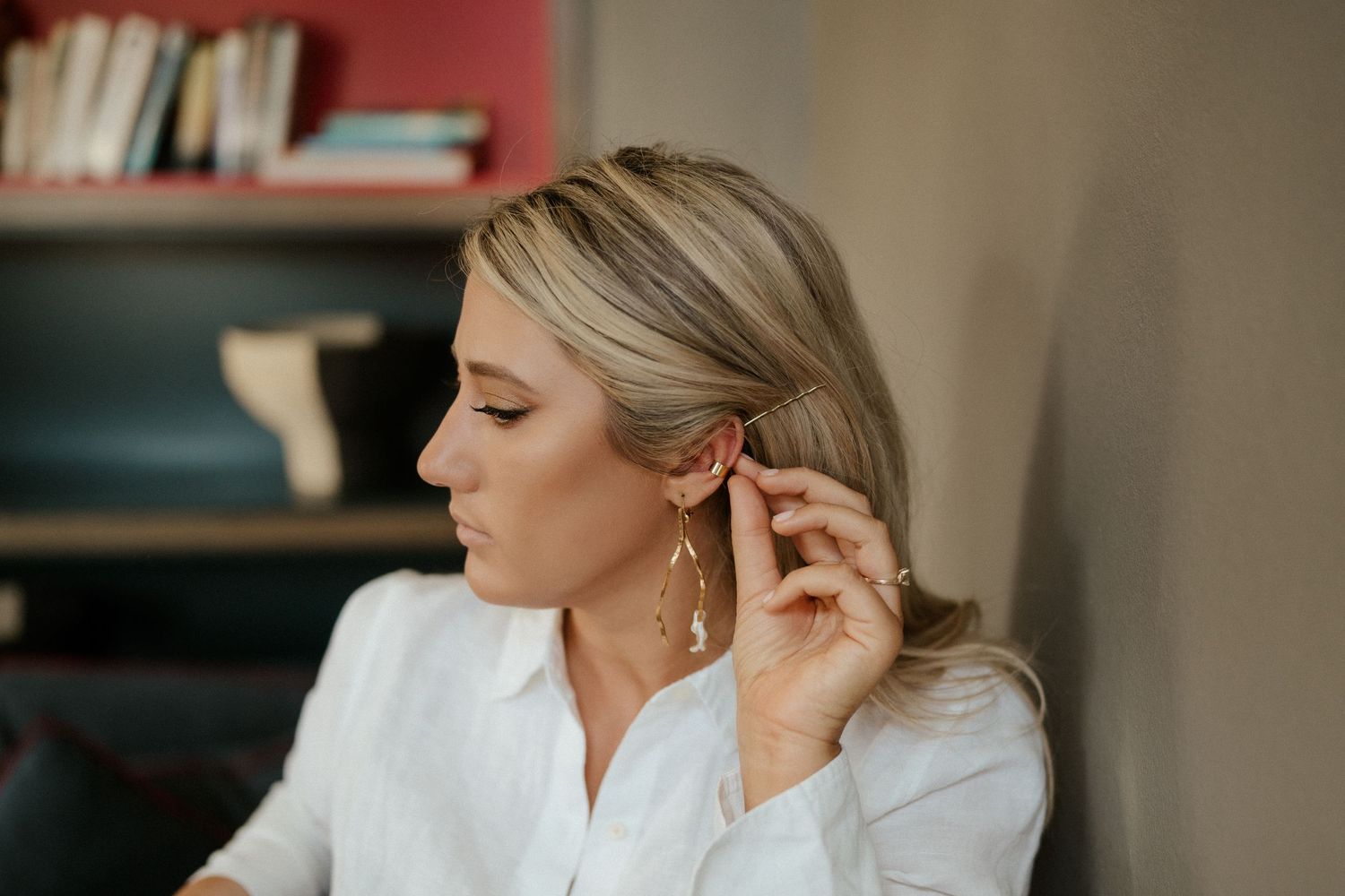 Elegant portrait in soft lighting showing delicate earring detail in an intimate indoor setting.