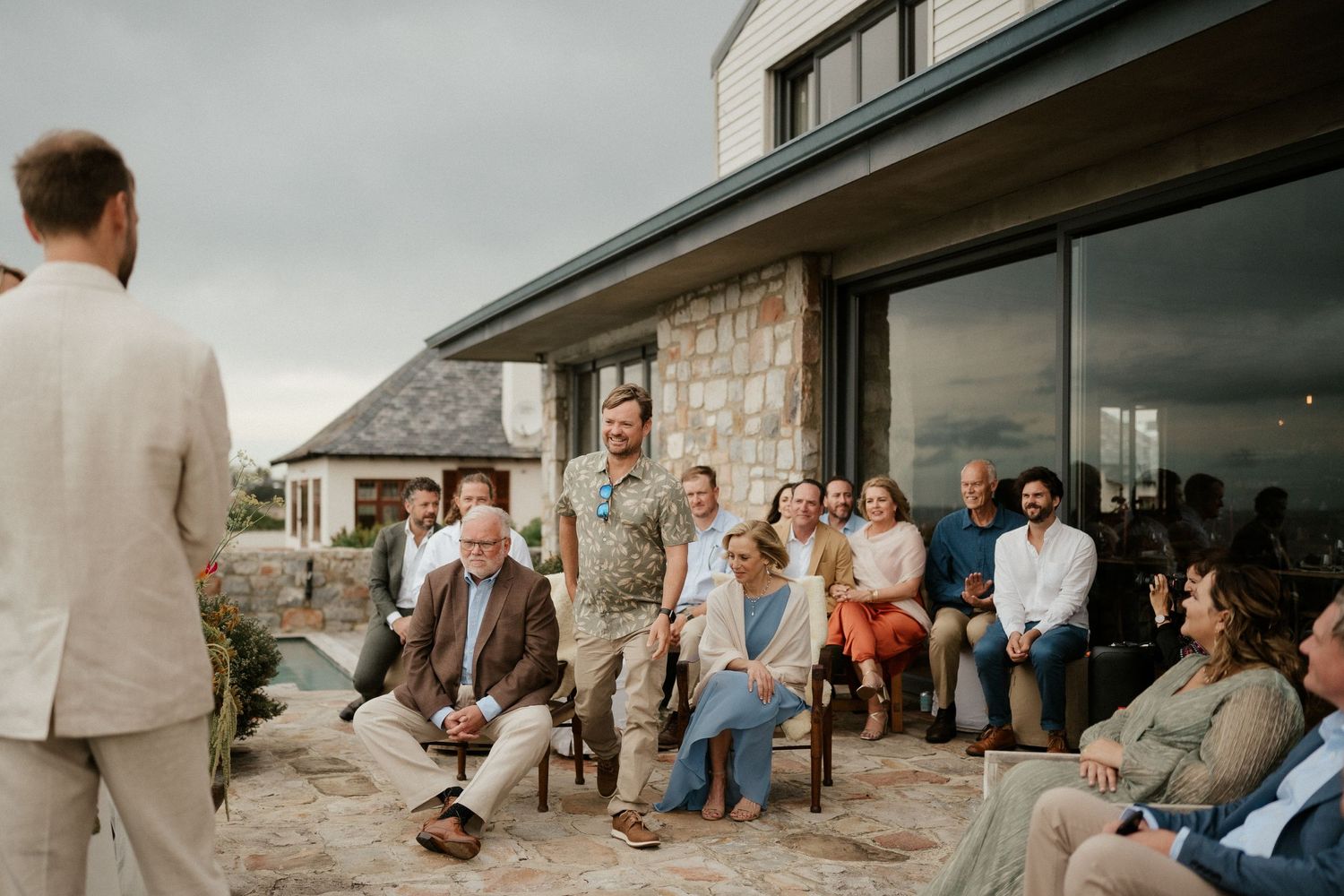 Guests seated on a stone patio during an outdoor wedding event.