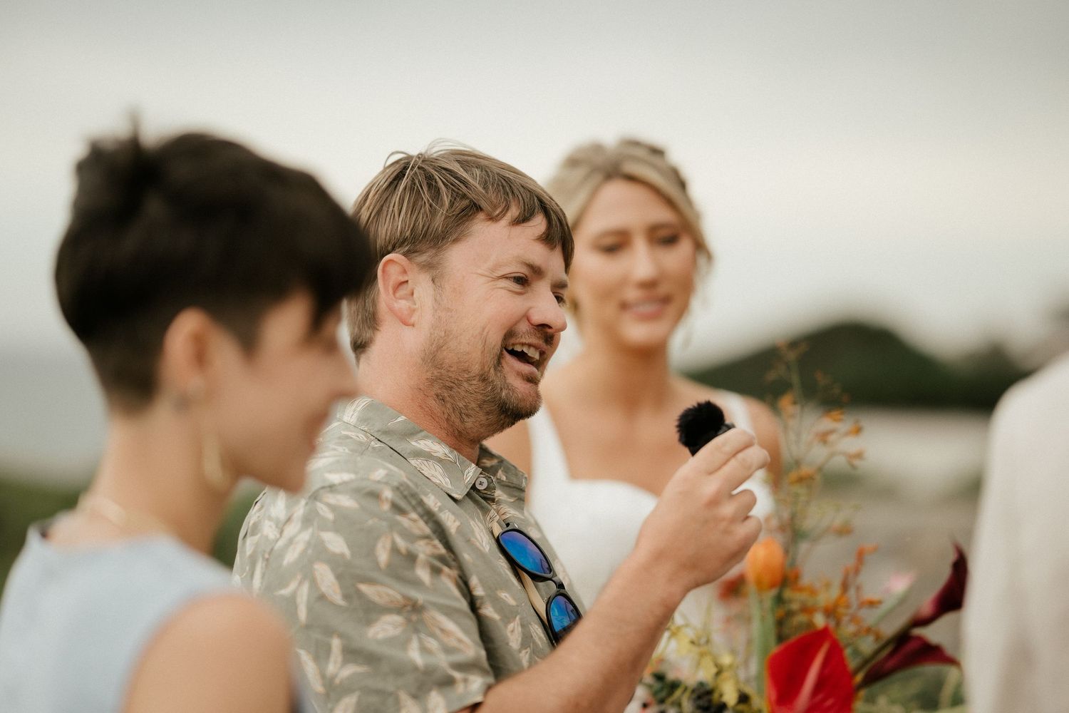 Joyful candid moment during outdoor wedding celebration with bright tropical flowers.