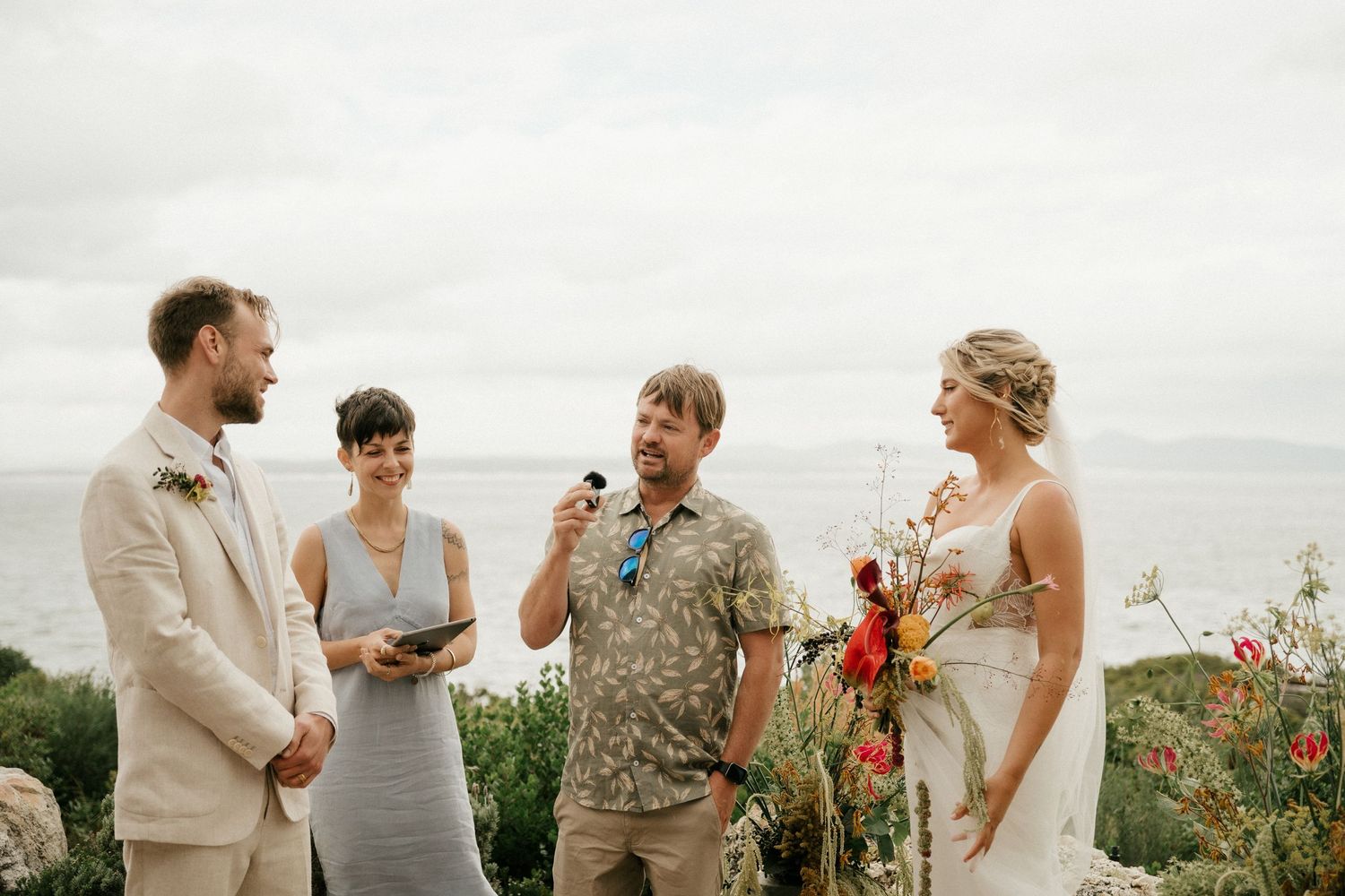 An intimate outdoor wedding ceremony takes place on a cliffside overlooking the ocean.