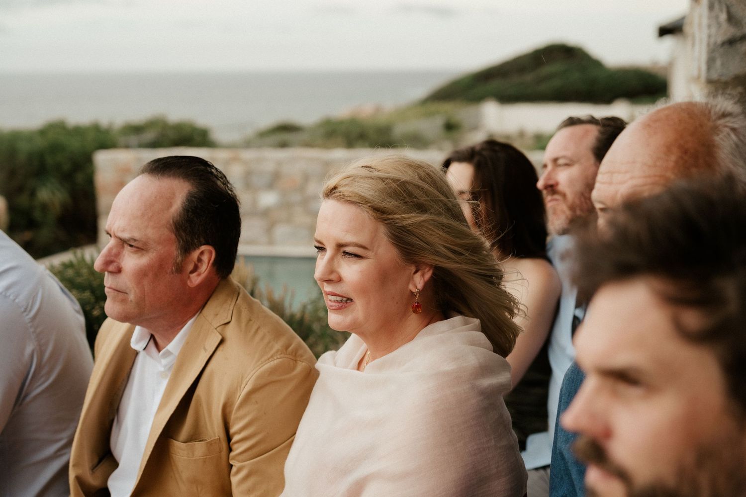 Wedding guests seated outdoors enjoying a coastal celebration.