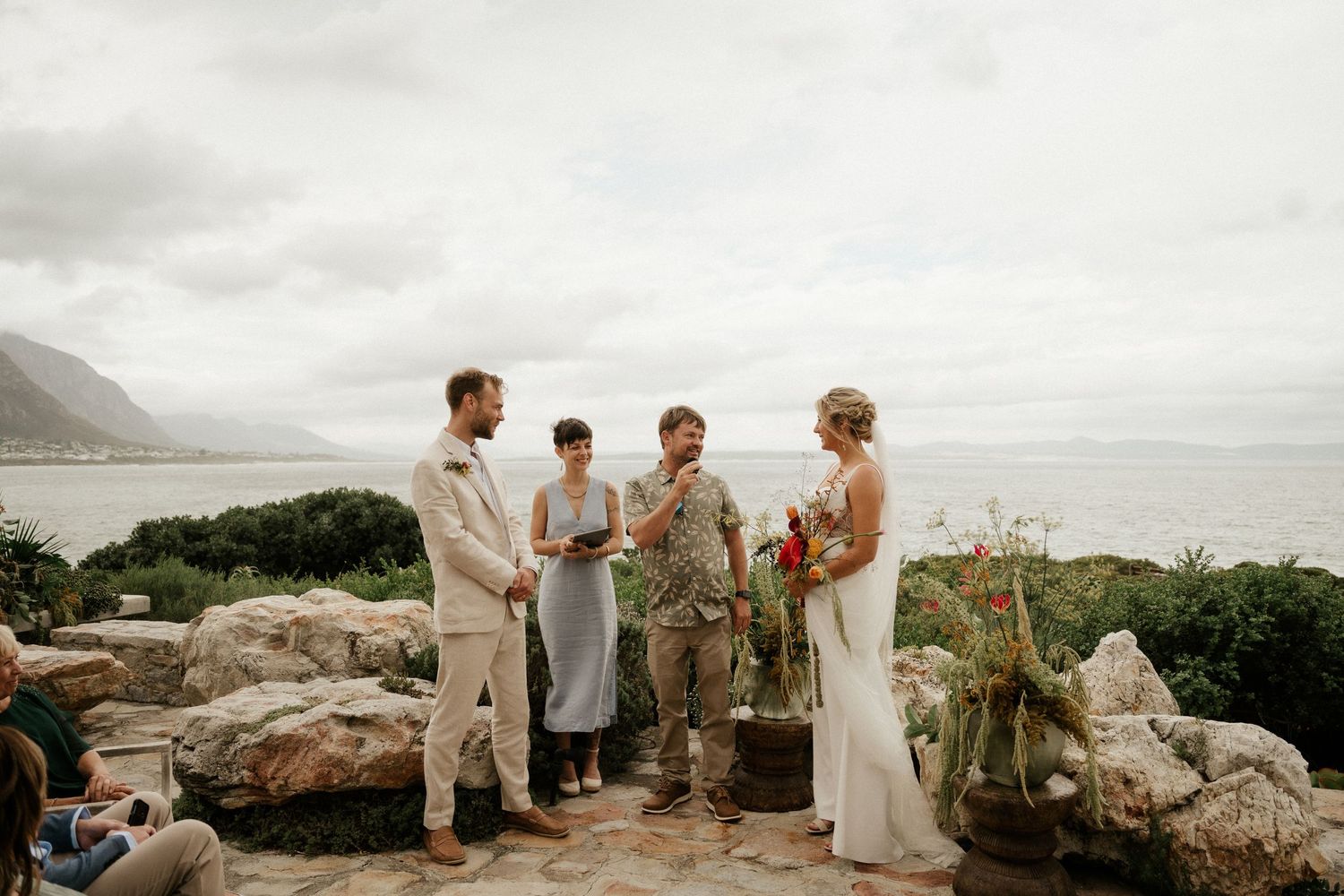A seaside wedding ceremony taking place on a rocky overlook with ocean views.