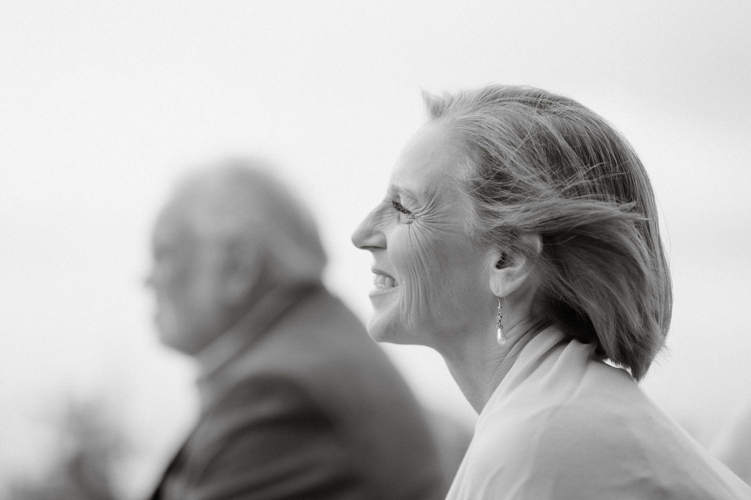 Black and white profile shot of a joyful wedding guest laughing.