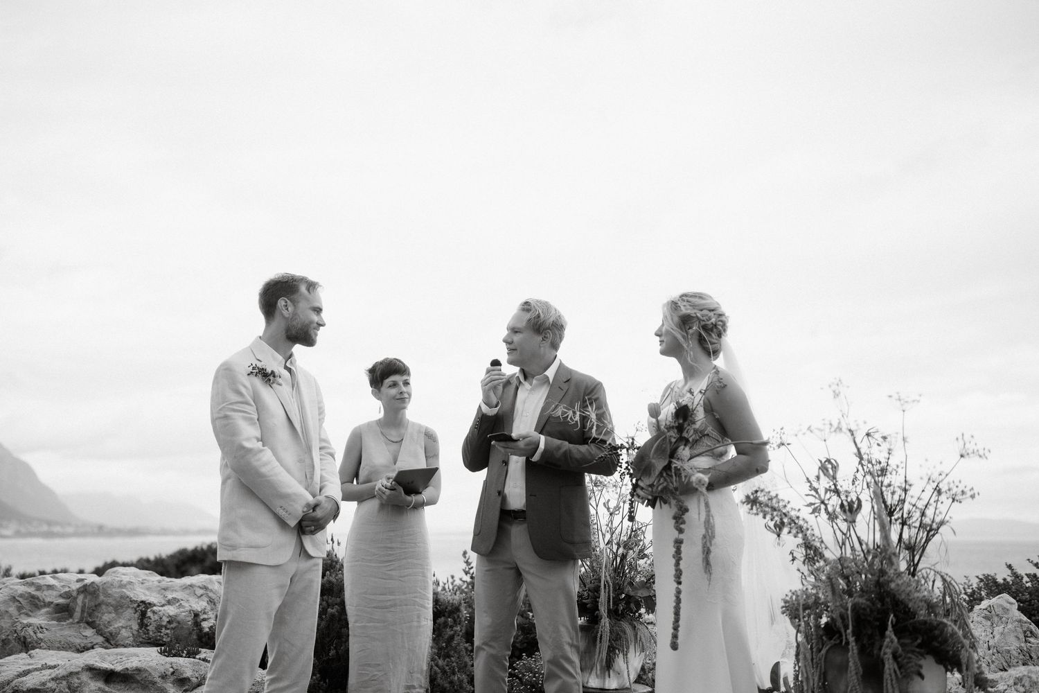 An intimate outdoor wedding ceremony takes place against a scenic mountain backdrop.