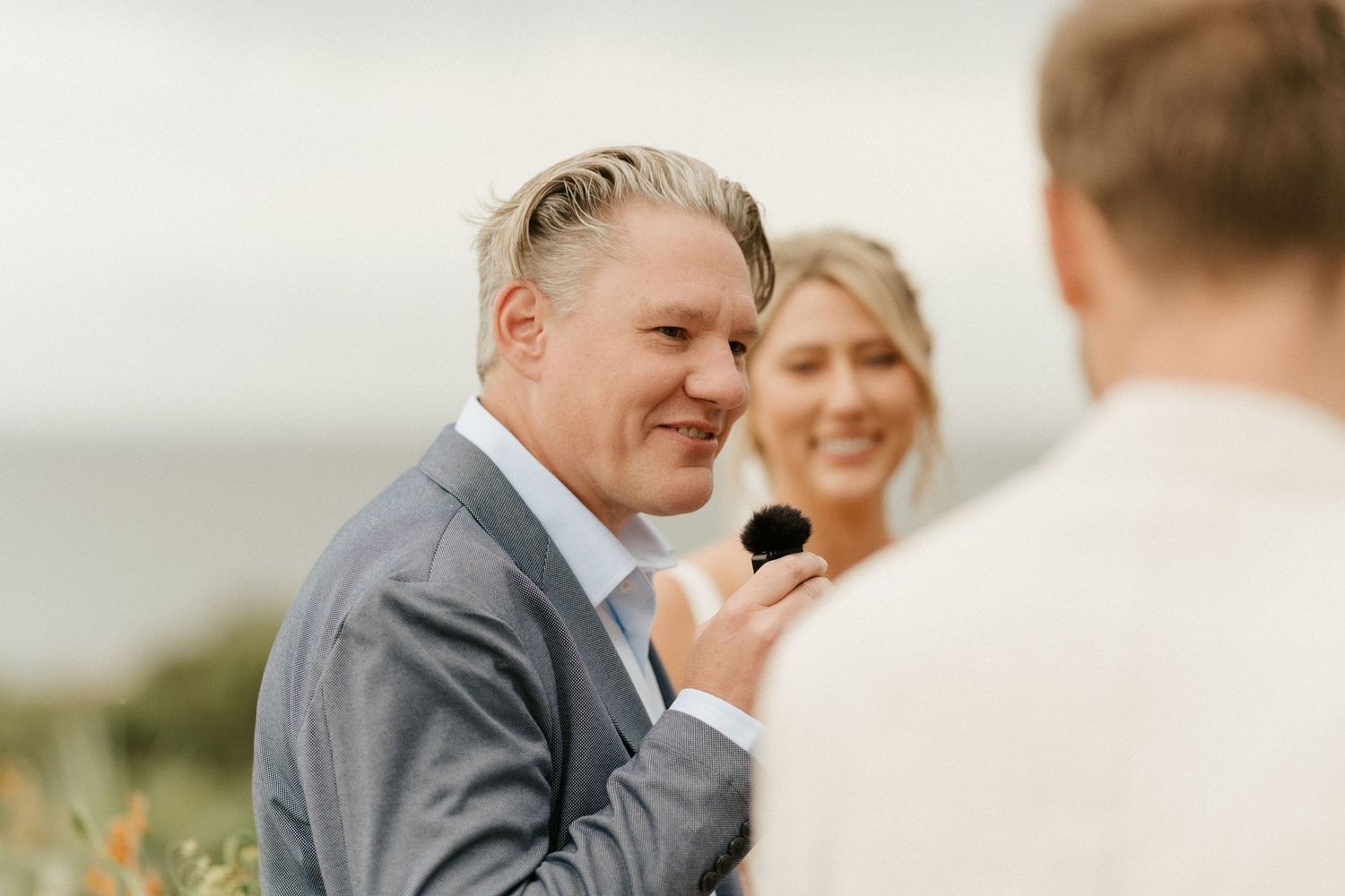 A candid moment during an outdoor wedding ceremony with ocean views.