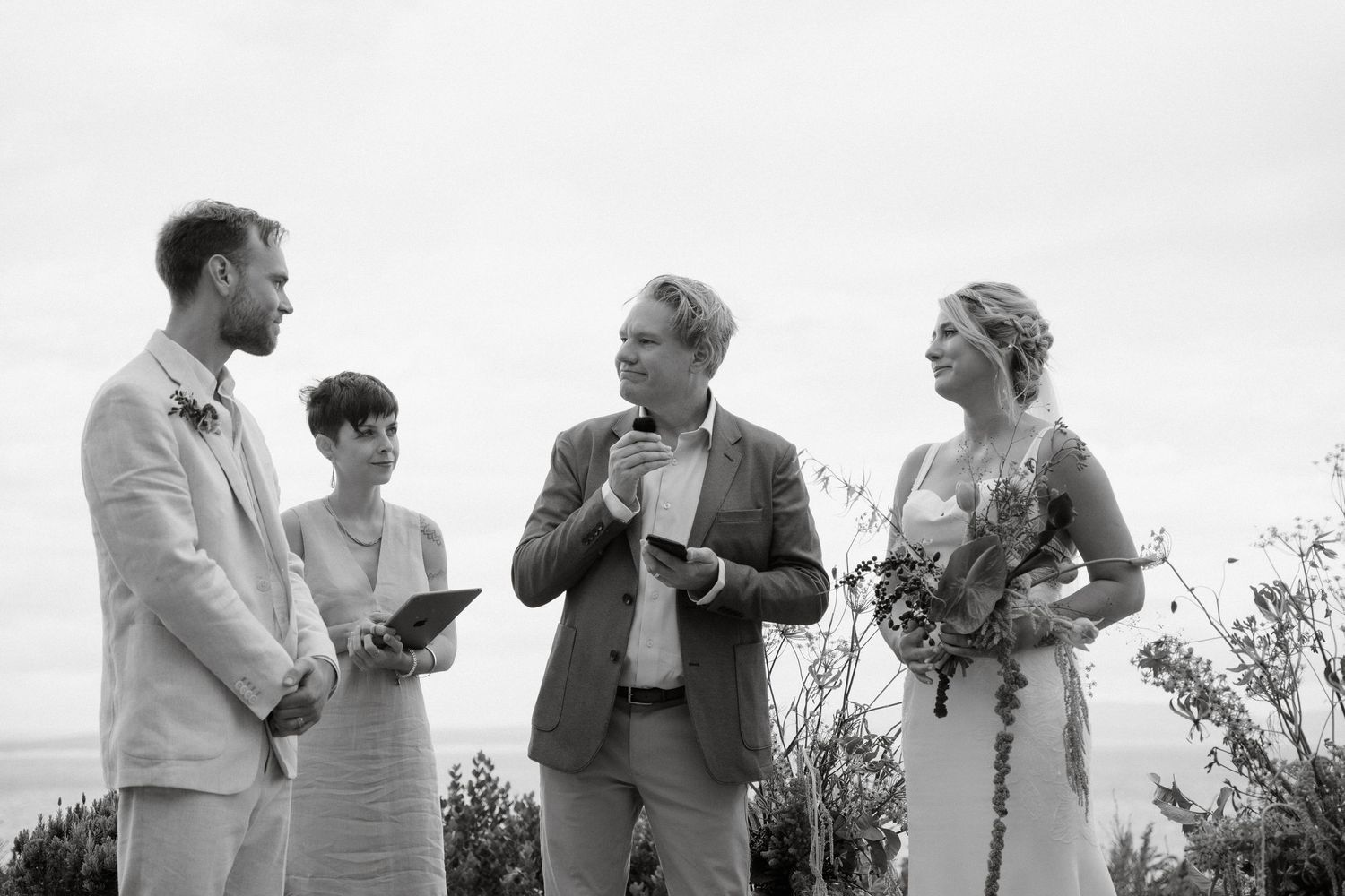 A black and white photo captures a small wedding ceremony group on a mountaintop.