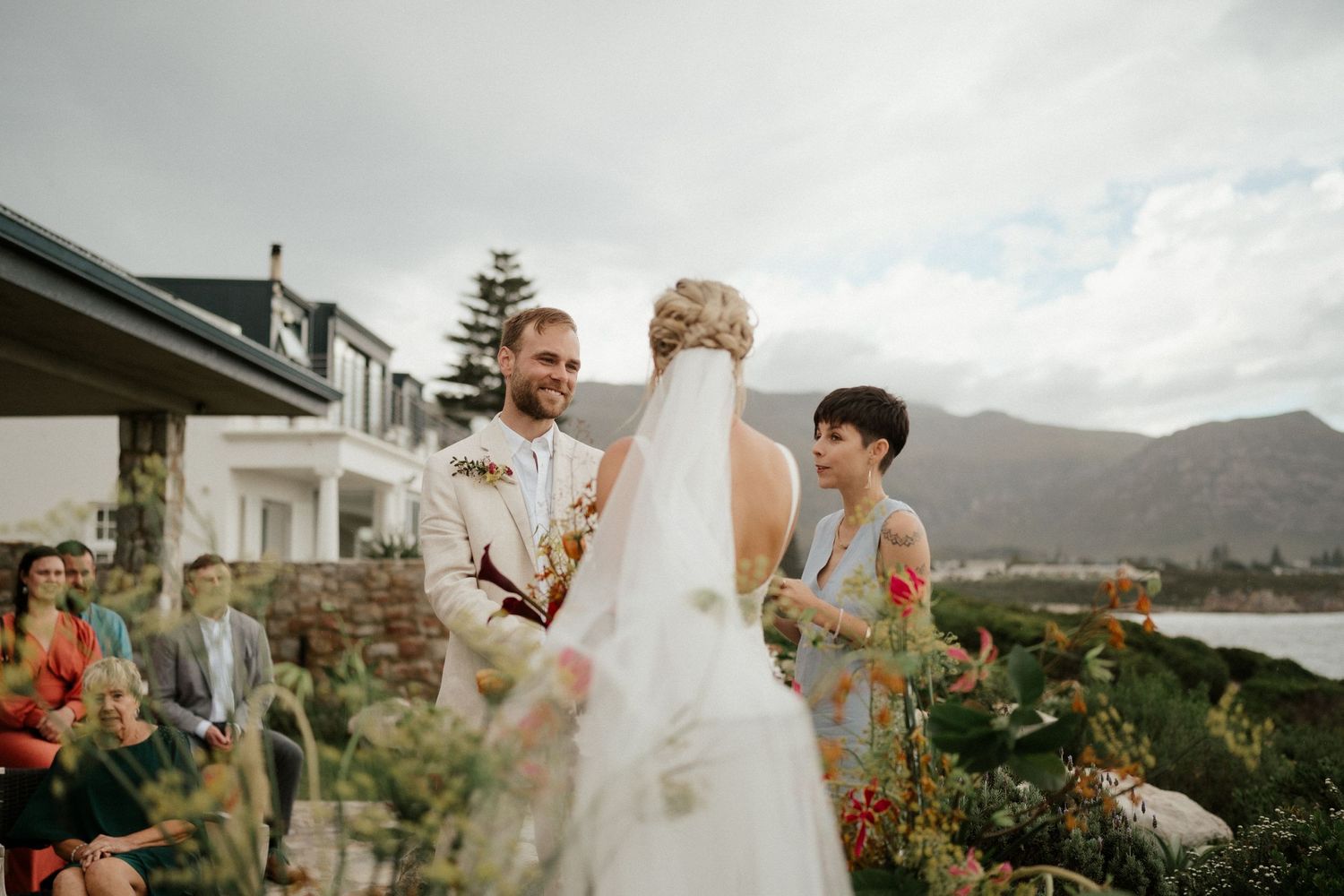 A wedding celebration unfolds in a garden setting with mountains visible in the background.