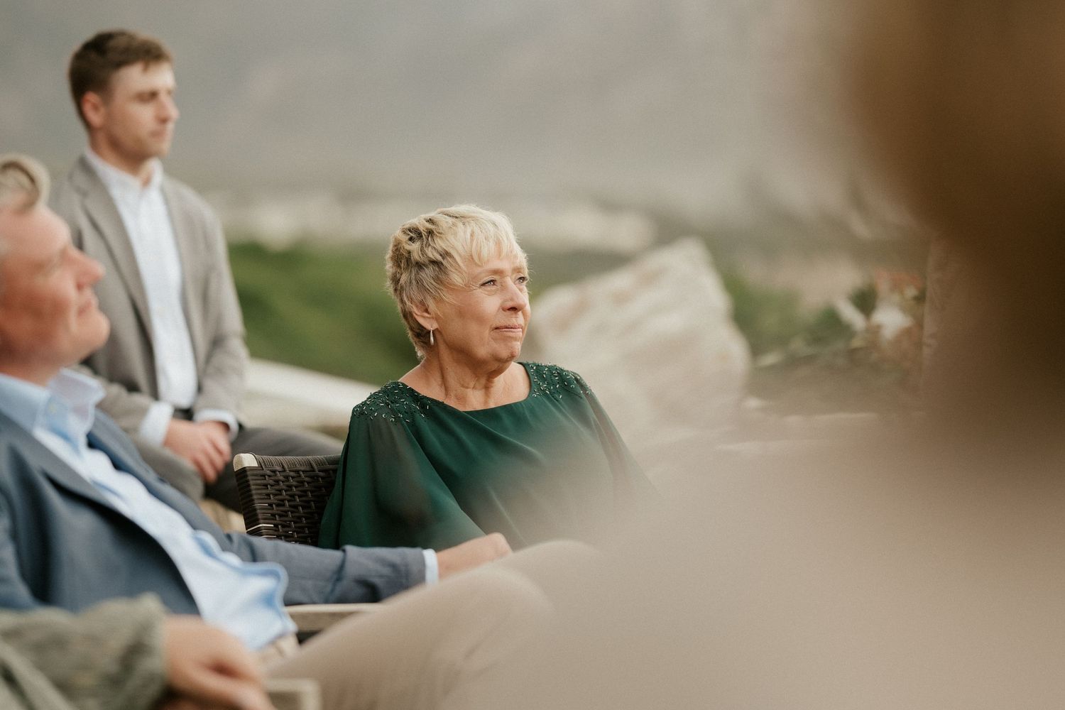Wedding guests seated outdoors watching an emotional ceremony moment at a sunny venue.