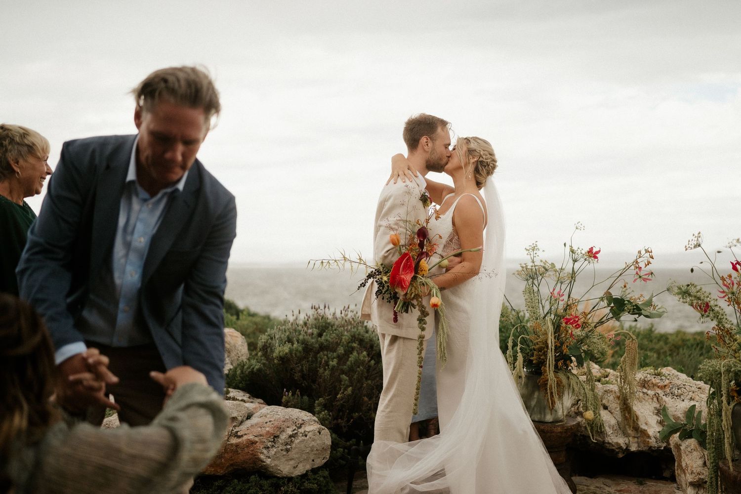 An intimate cliffside wedding ceremony surrounded by natural landscaping and moody skies.