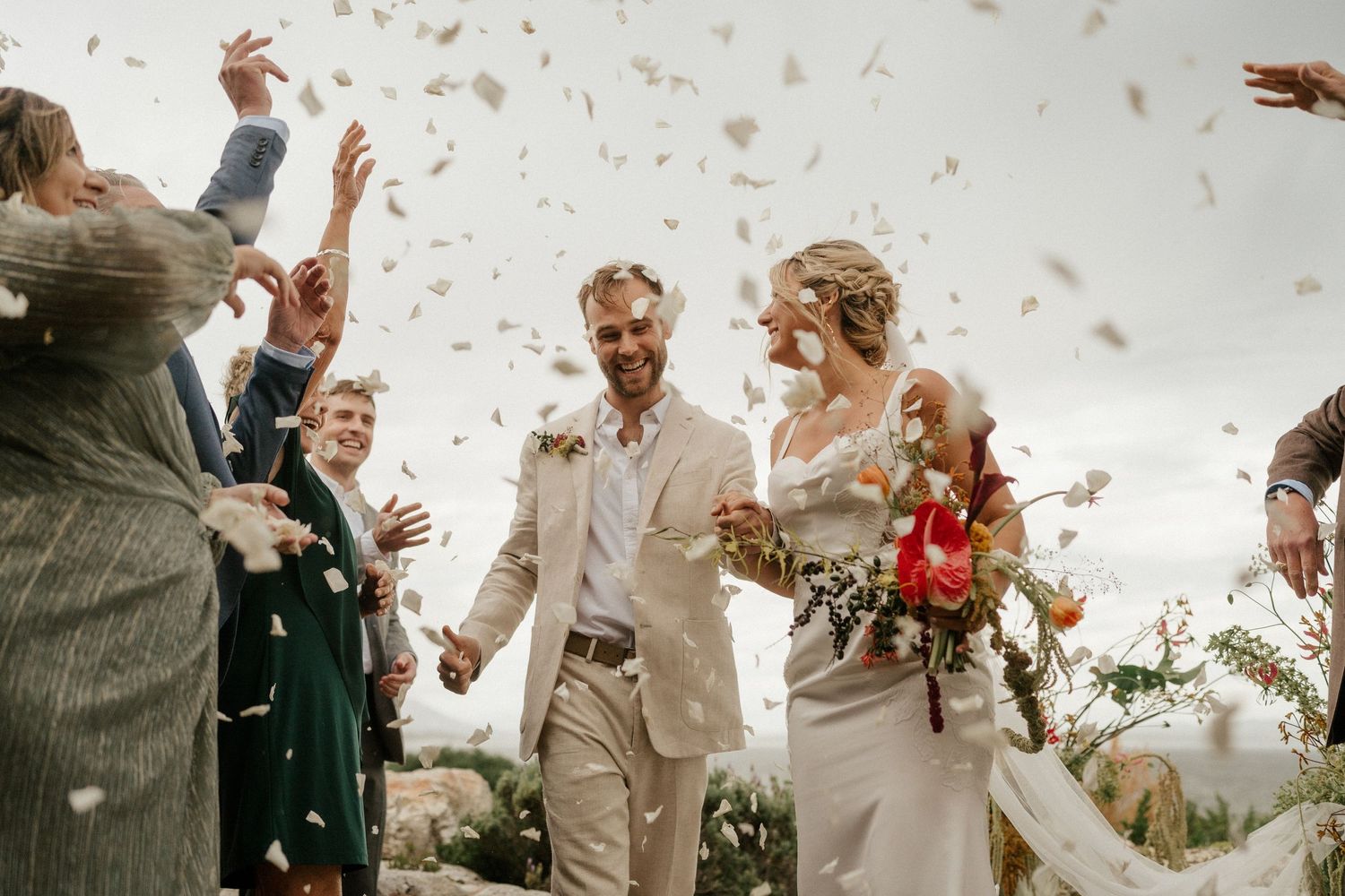 Wedding guests shower a couple with confetti in a joyful outdoor celebration.