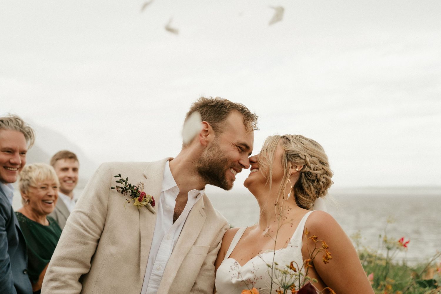 A romantic moment shared between newlyweds during their outdoor seaside wedding ceremony.