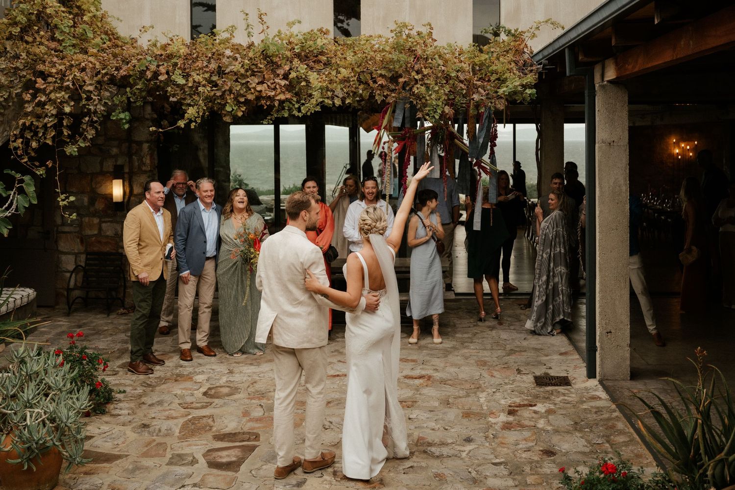 A couple dancing on a stone patio surrounded by guests at an outdoor celebration.
