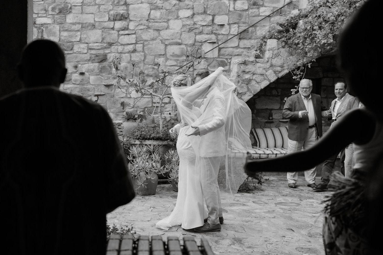 Black and white photo of a wedding celebration in front of a stone wall.