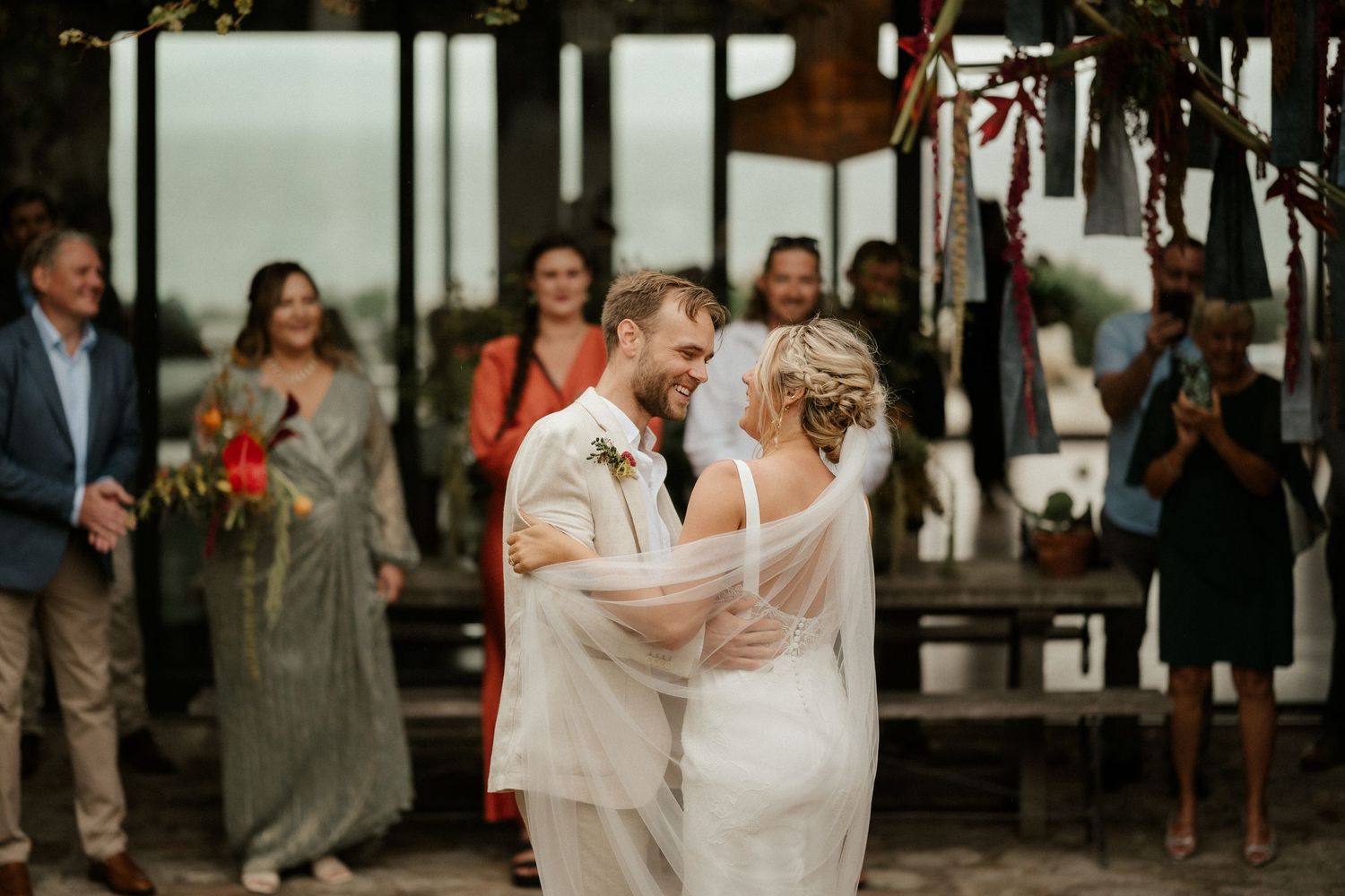 A couple sharing their first dance while wedding guests watch and celebrate.