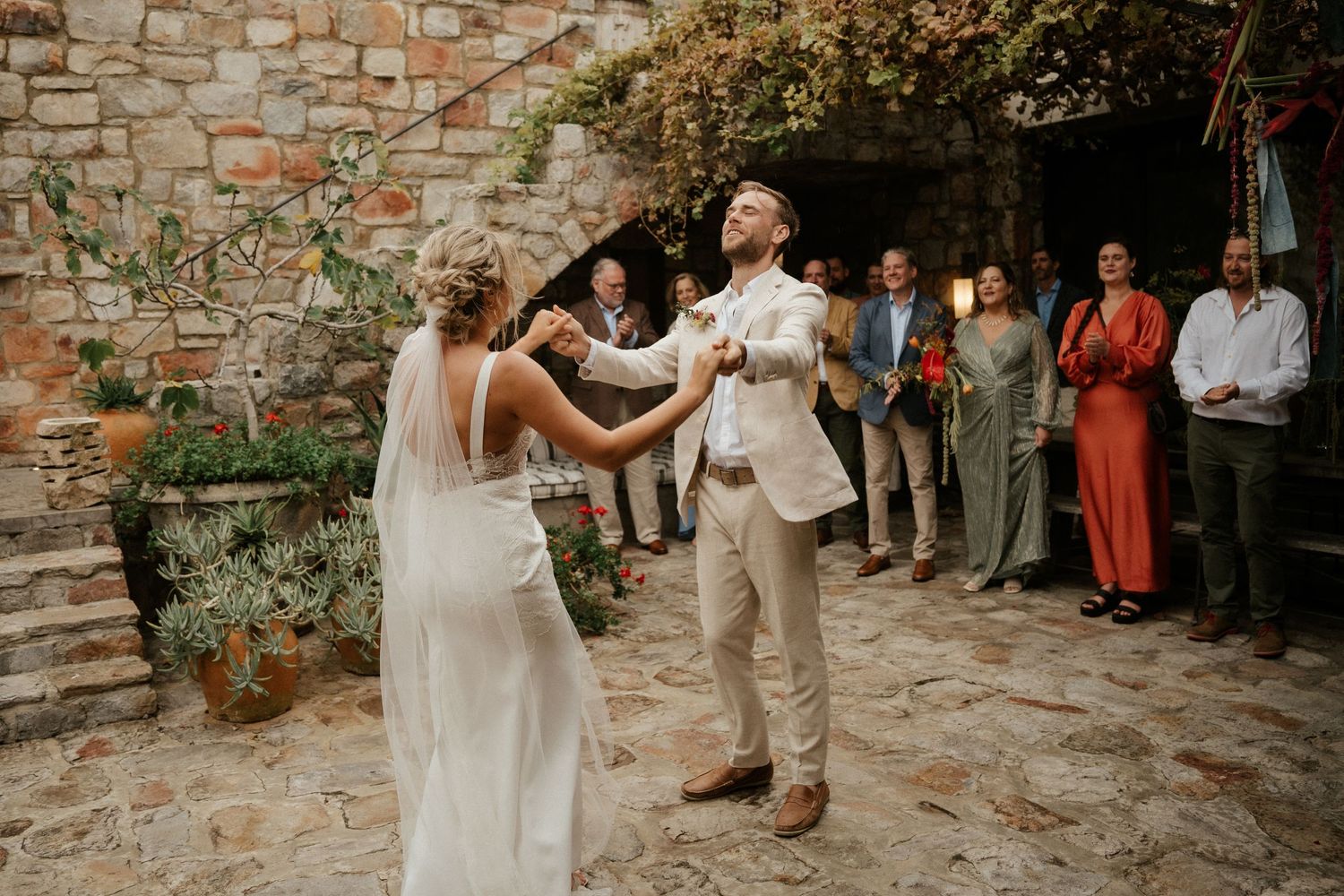 Wedding celebration in a rustic stone courtyard with guests watching the festivities.