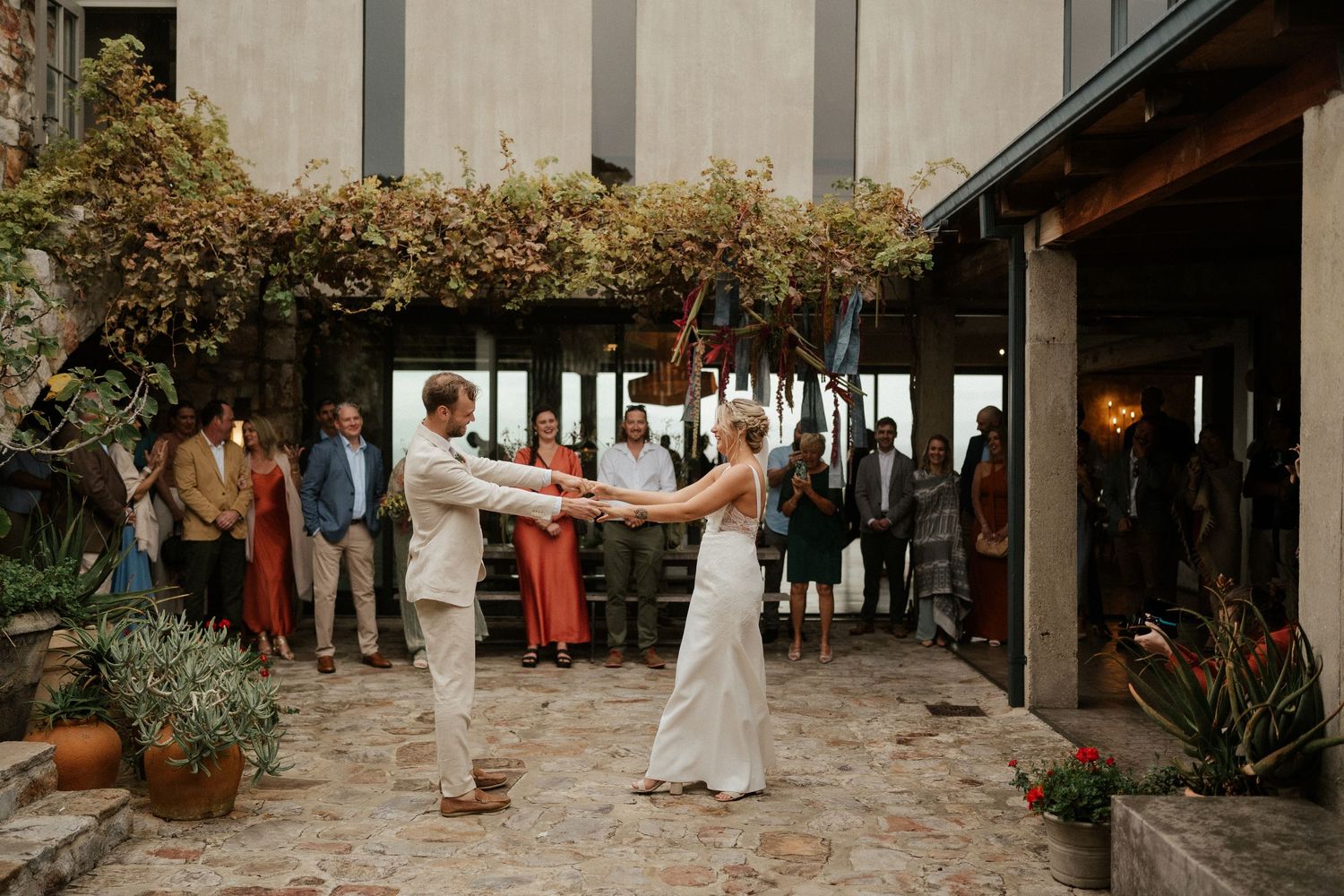A reception dance in a rustic courtyard setting with string lights and greenery.