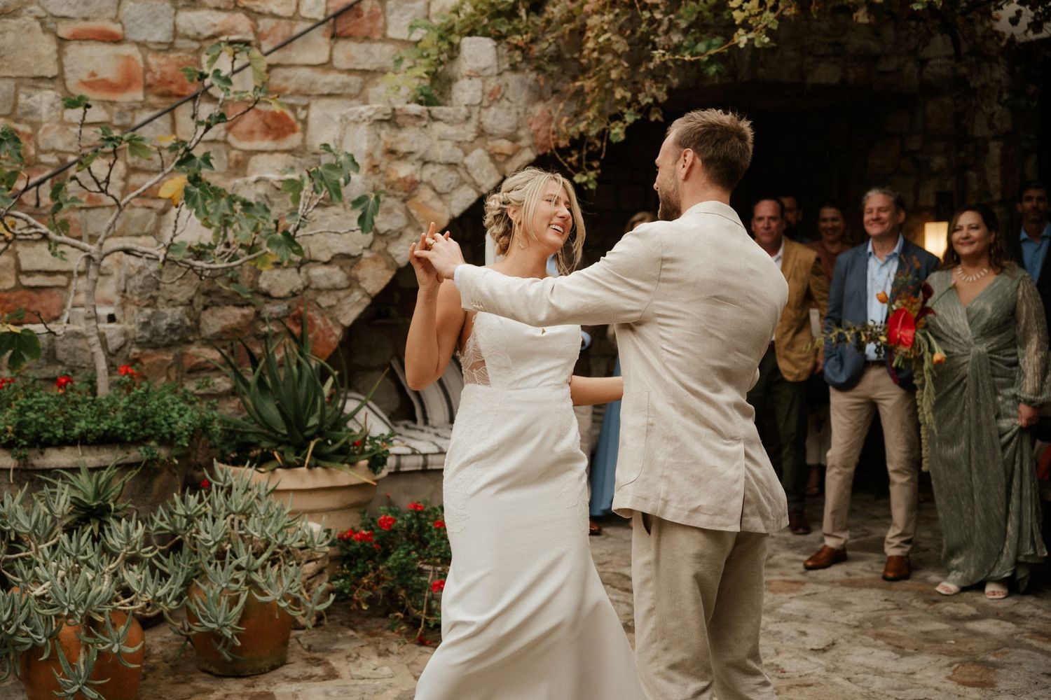 A couple dancing together on a stone patio during a wedding celebration.