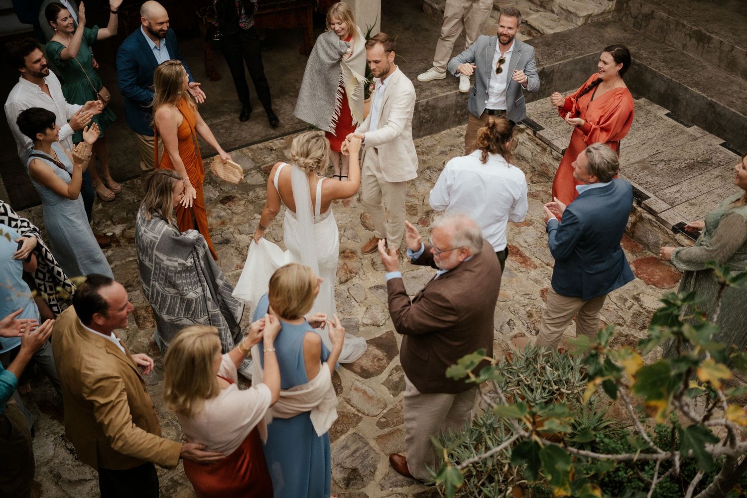 Aerial view of wedding guests mingling in a rustic stone courtyard.