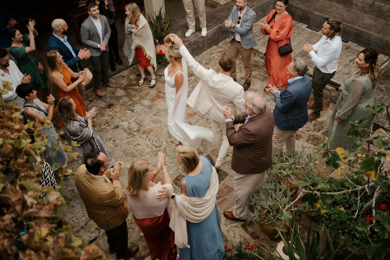 Wedding guests form a circle around dancers during an intimate outdoor celebration.